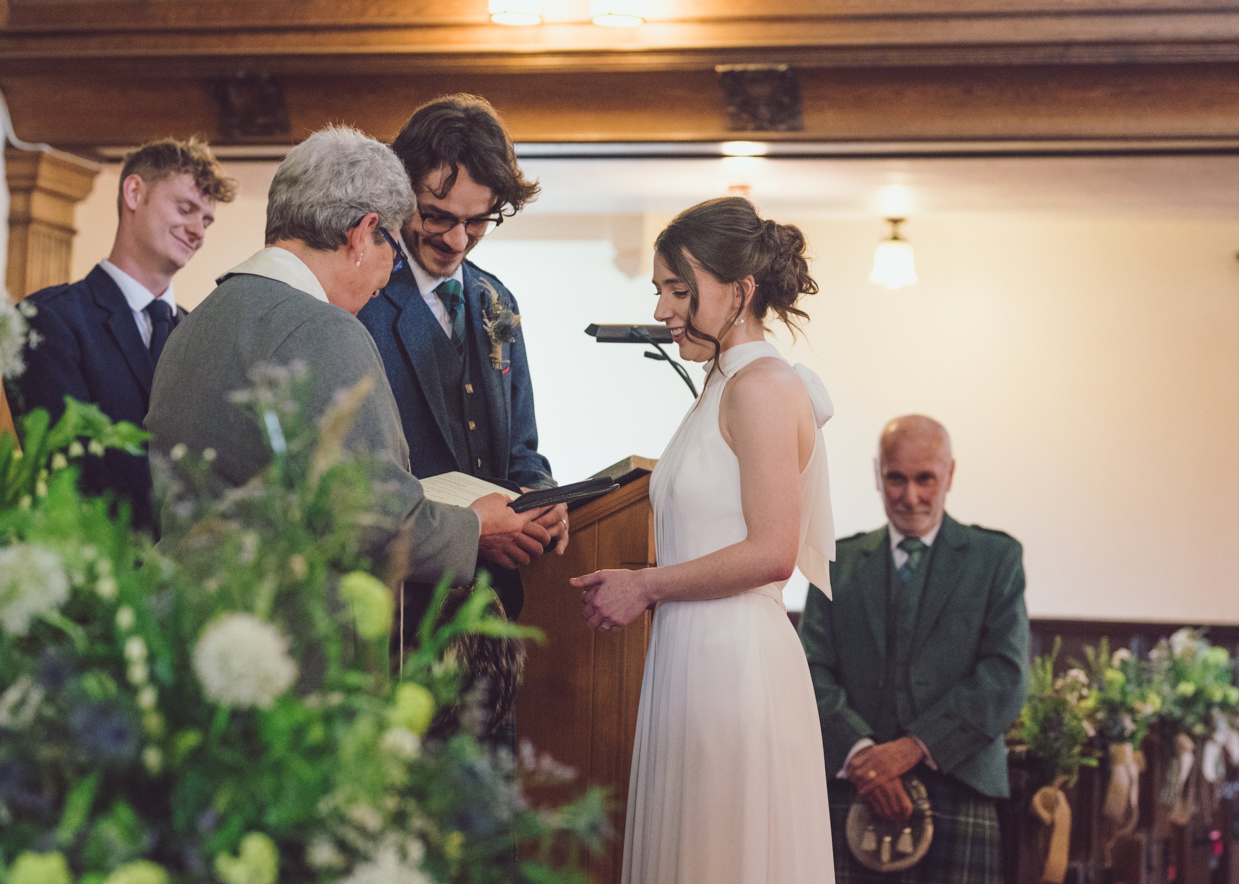 Bride smiling during her wedding ceremony with family and friends watching