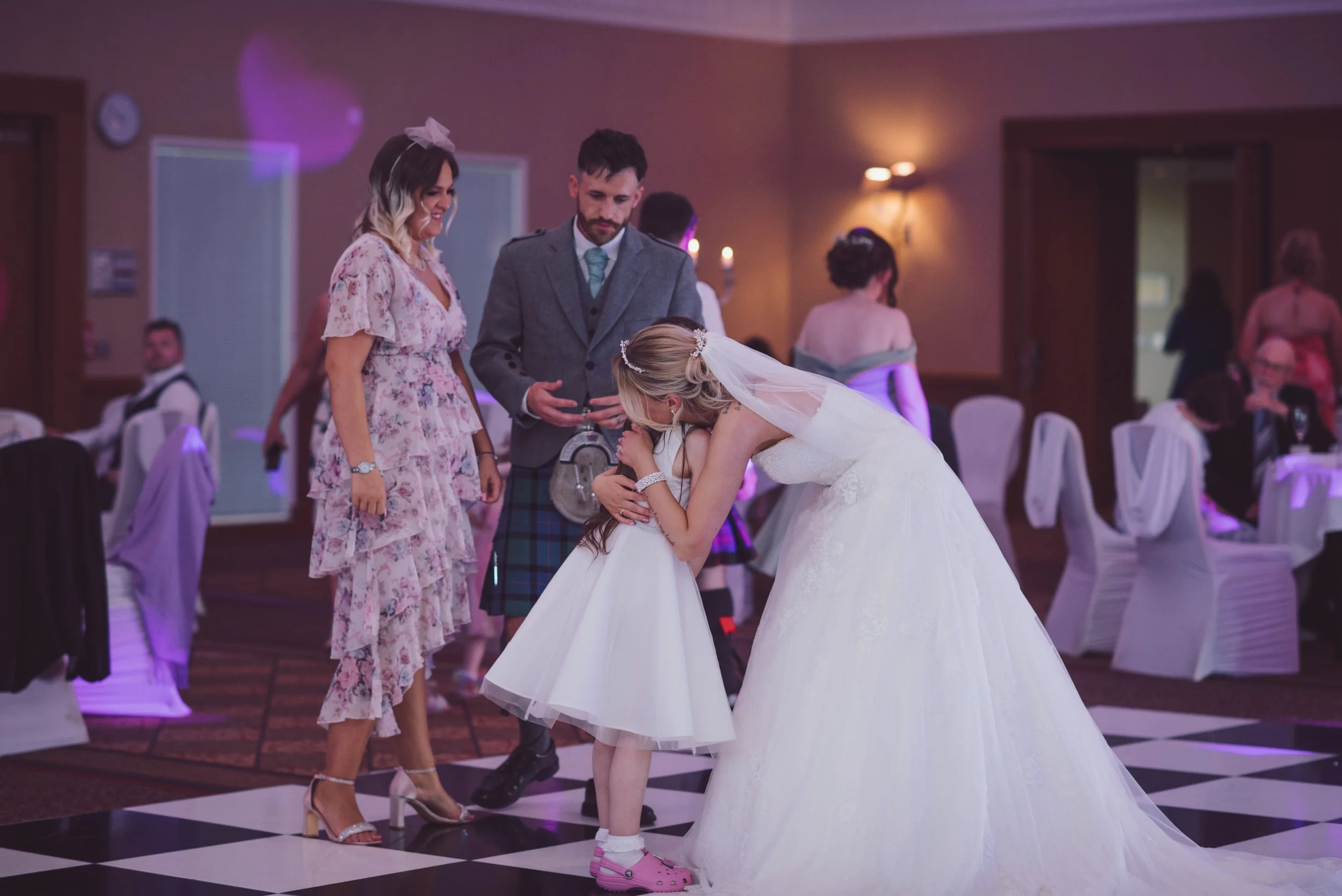 Bride and groom enjoying a special moment with a young flower girl during their wedding reception