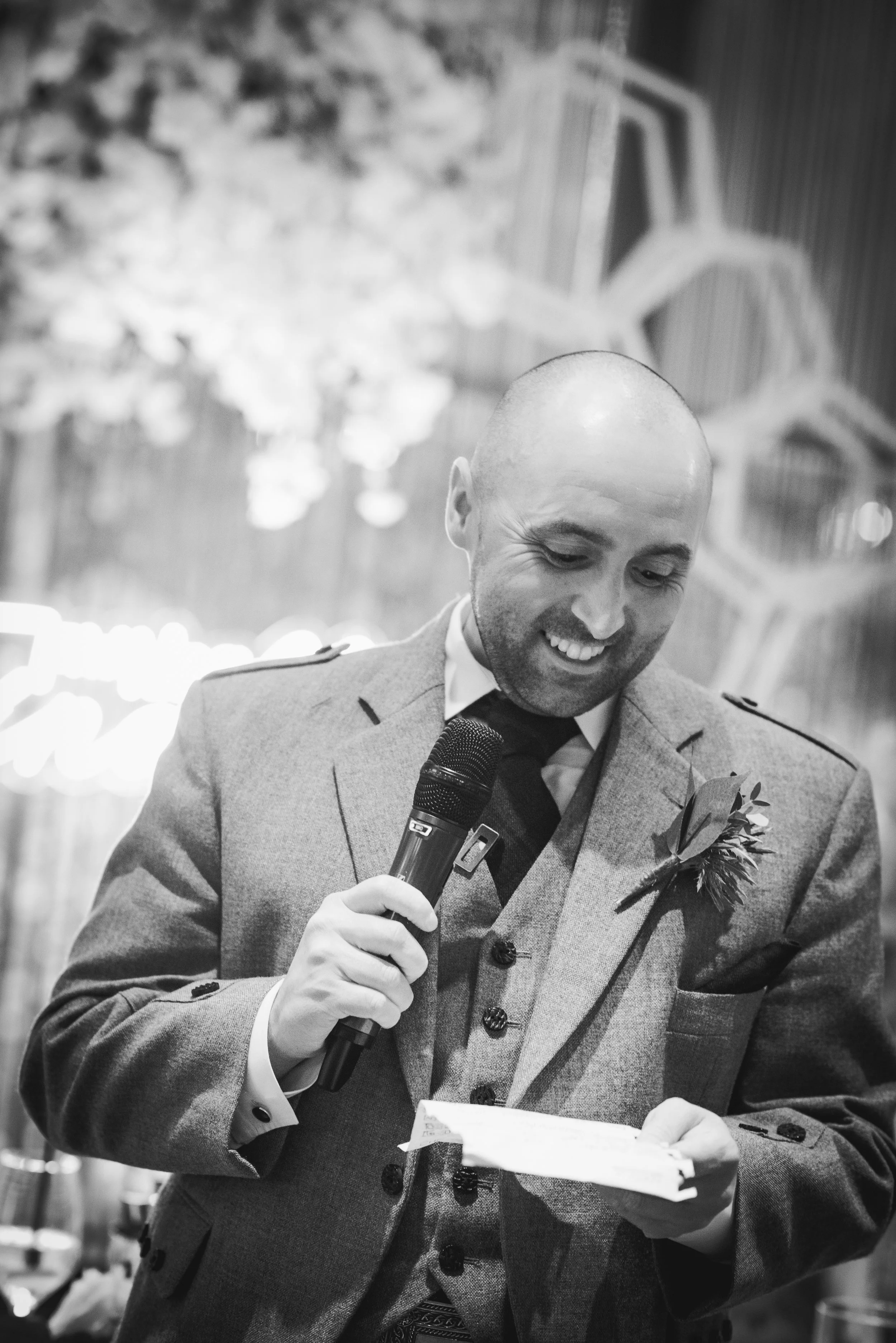Groom laughing during his wedding speech at his wedding reception, capturing a relaxed and joyful moment