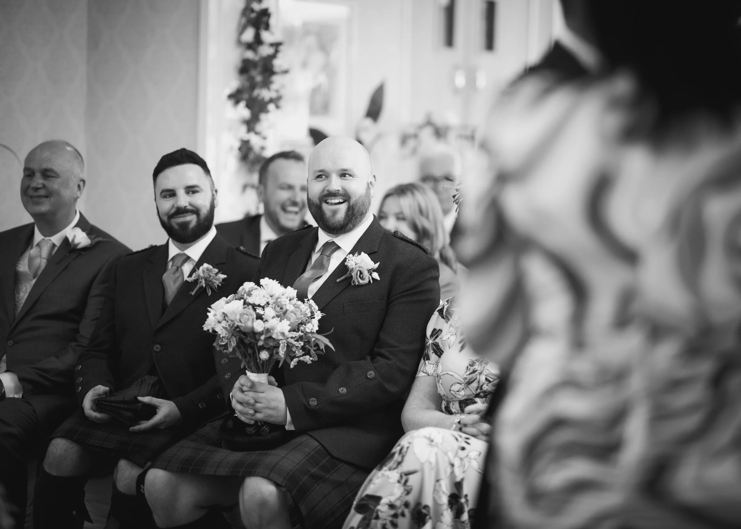 Groom laughing with wedding guests during the ceremony