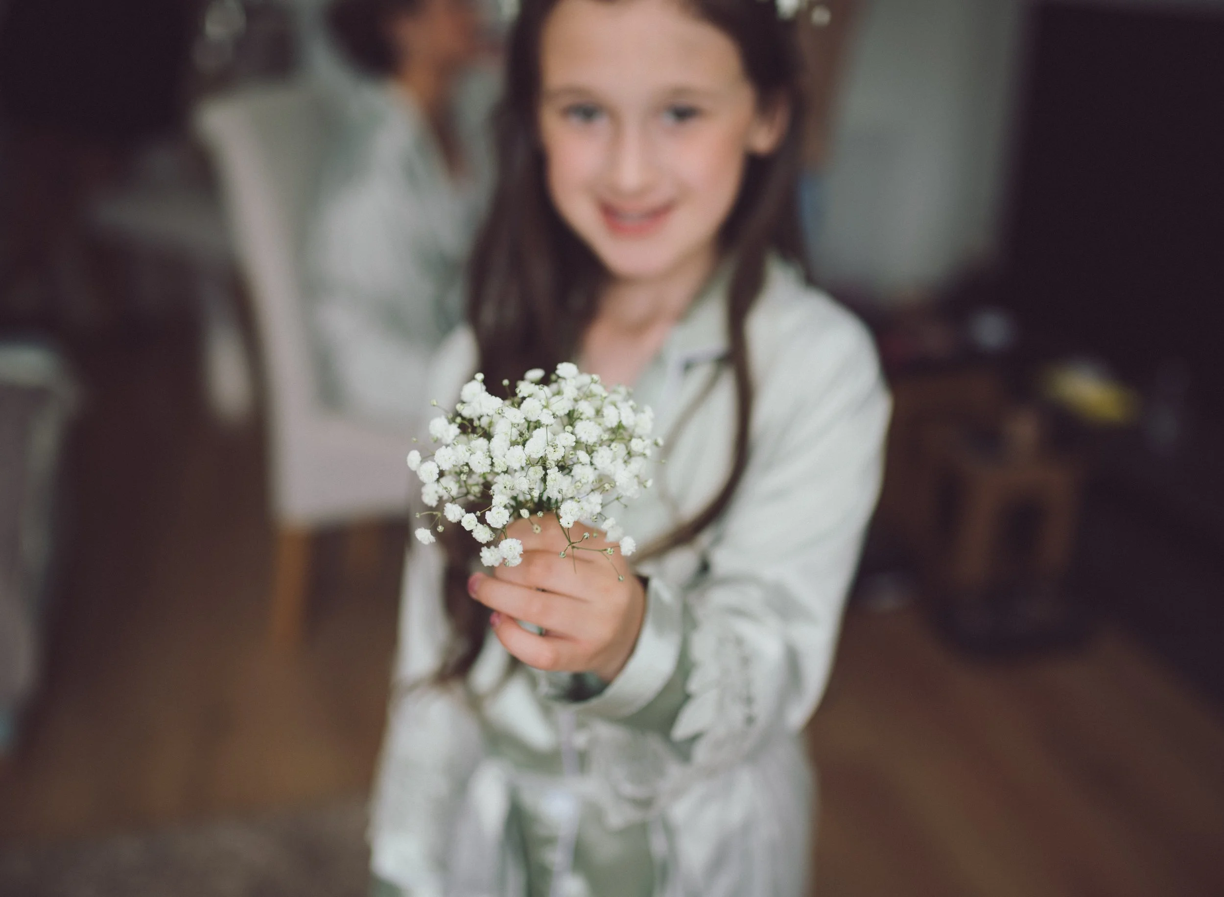 Flower girl holding a small bouquet during wedding preparations
