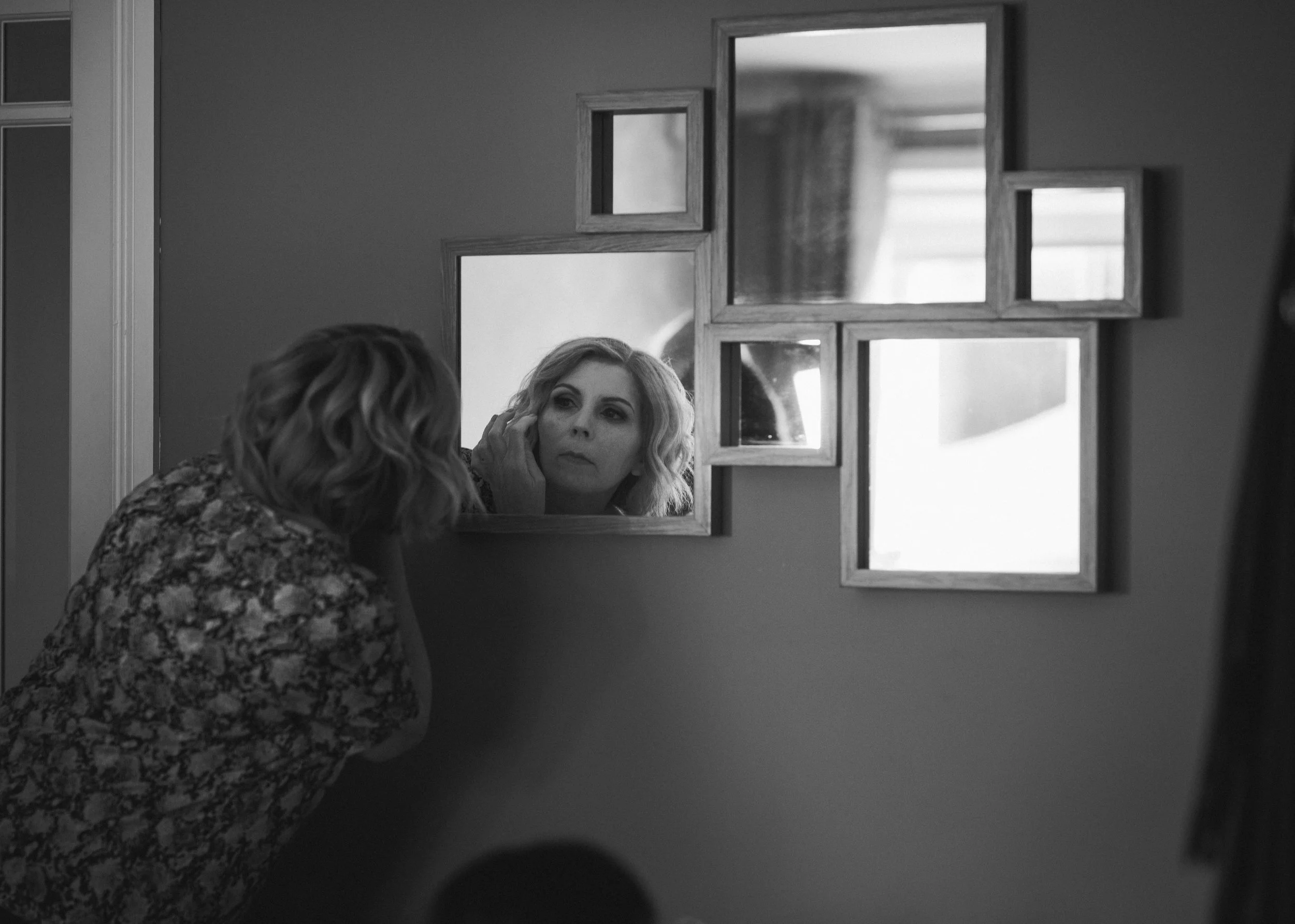 Mother of the bride checking her reflection in the mirror during wedding preparations