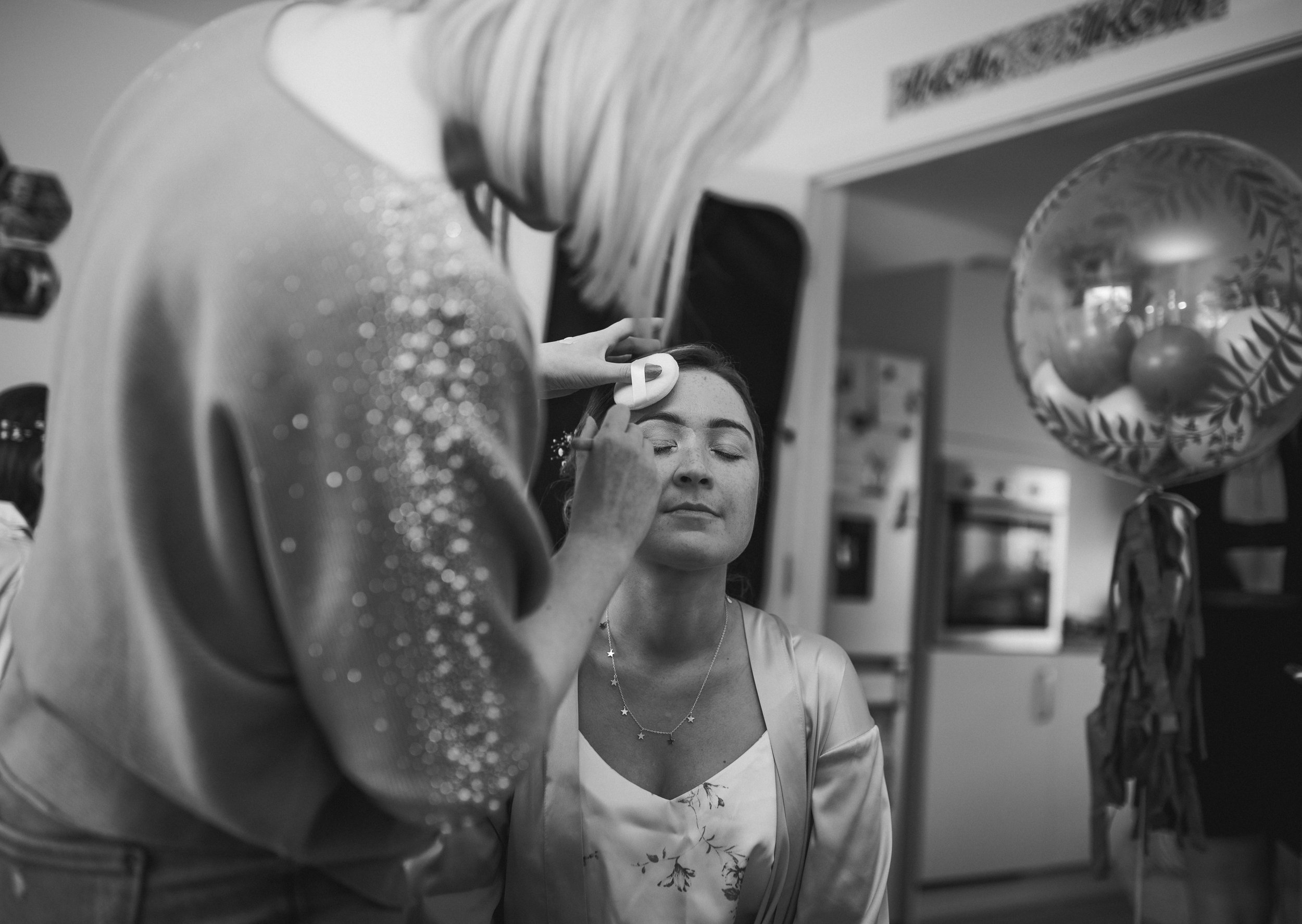 Bridesmaid having her makeup finished during relaxed wedding preparations