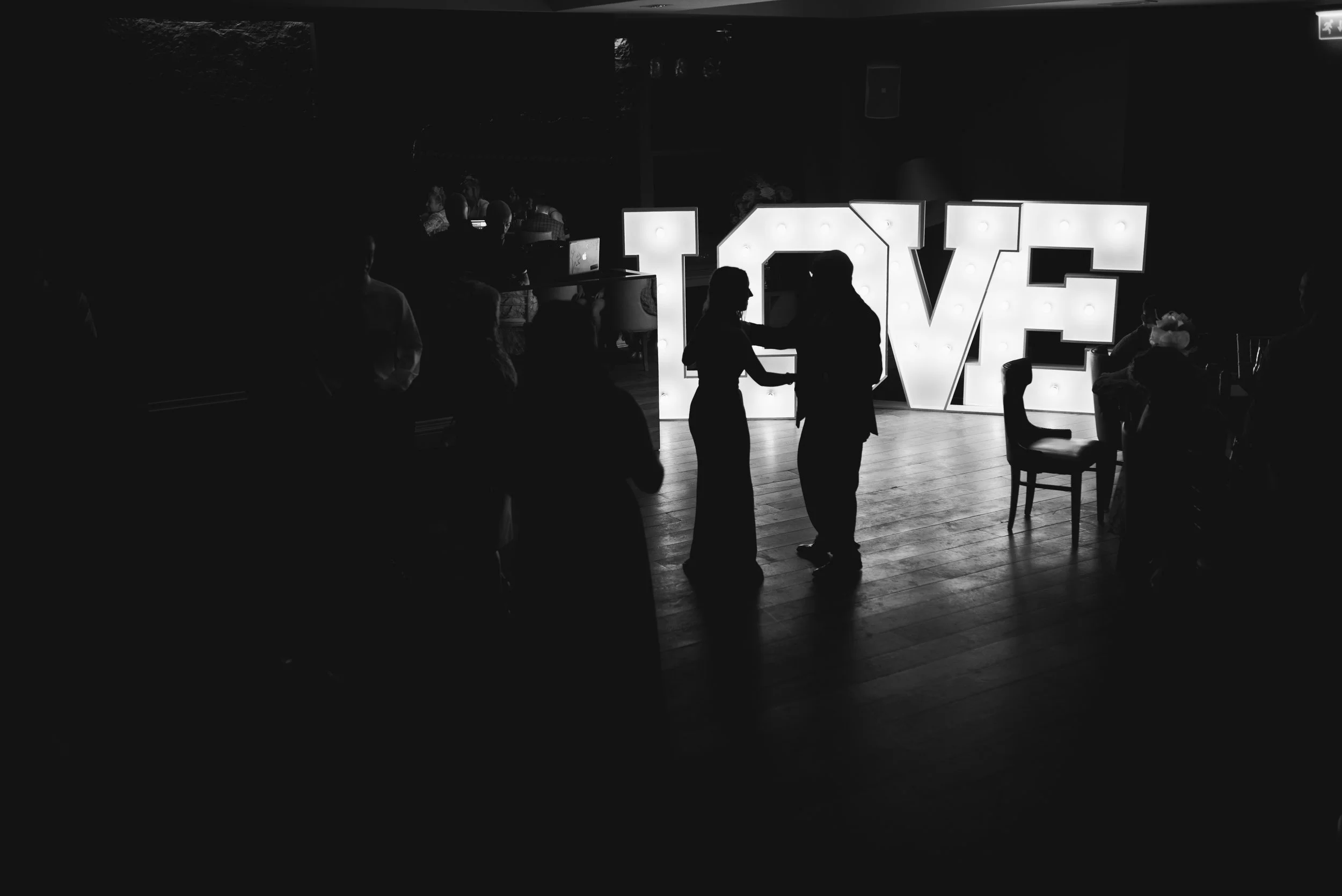 Couple dancing together beneath illuminated LOVE letters at their Glasgow wedding reception