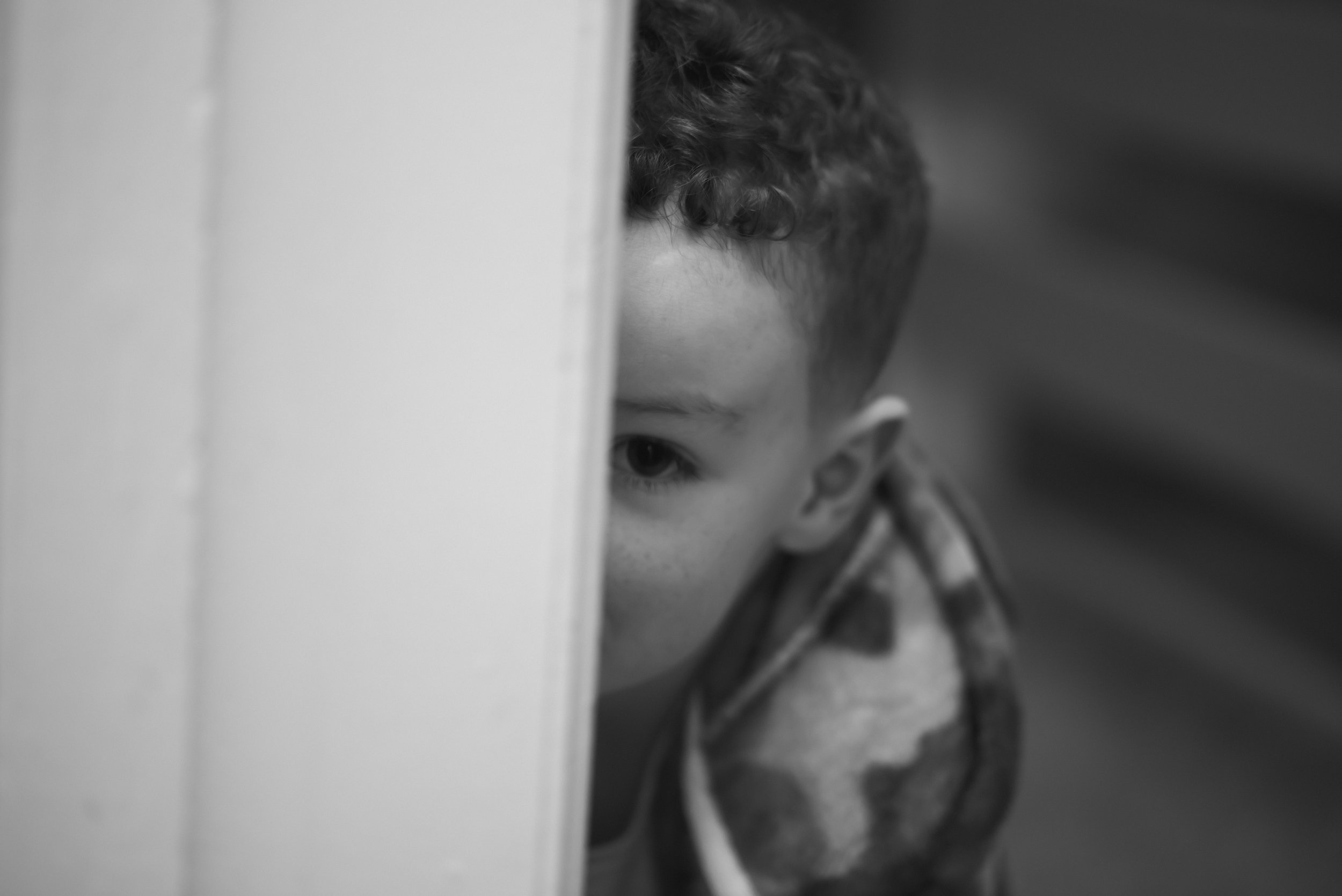 Young wedding guest peeking around a doorway during the celebrations