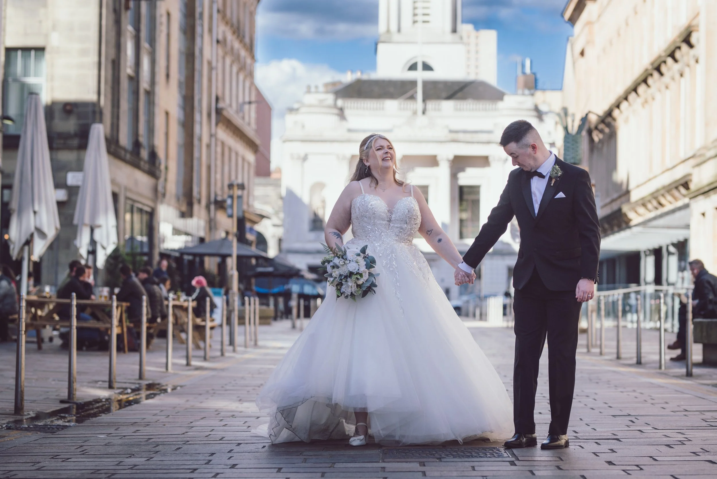 Bride and groom walking through Glasgow city centre on their wedding day