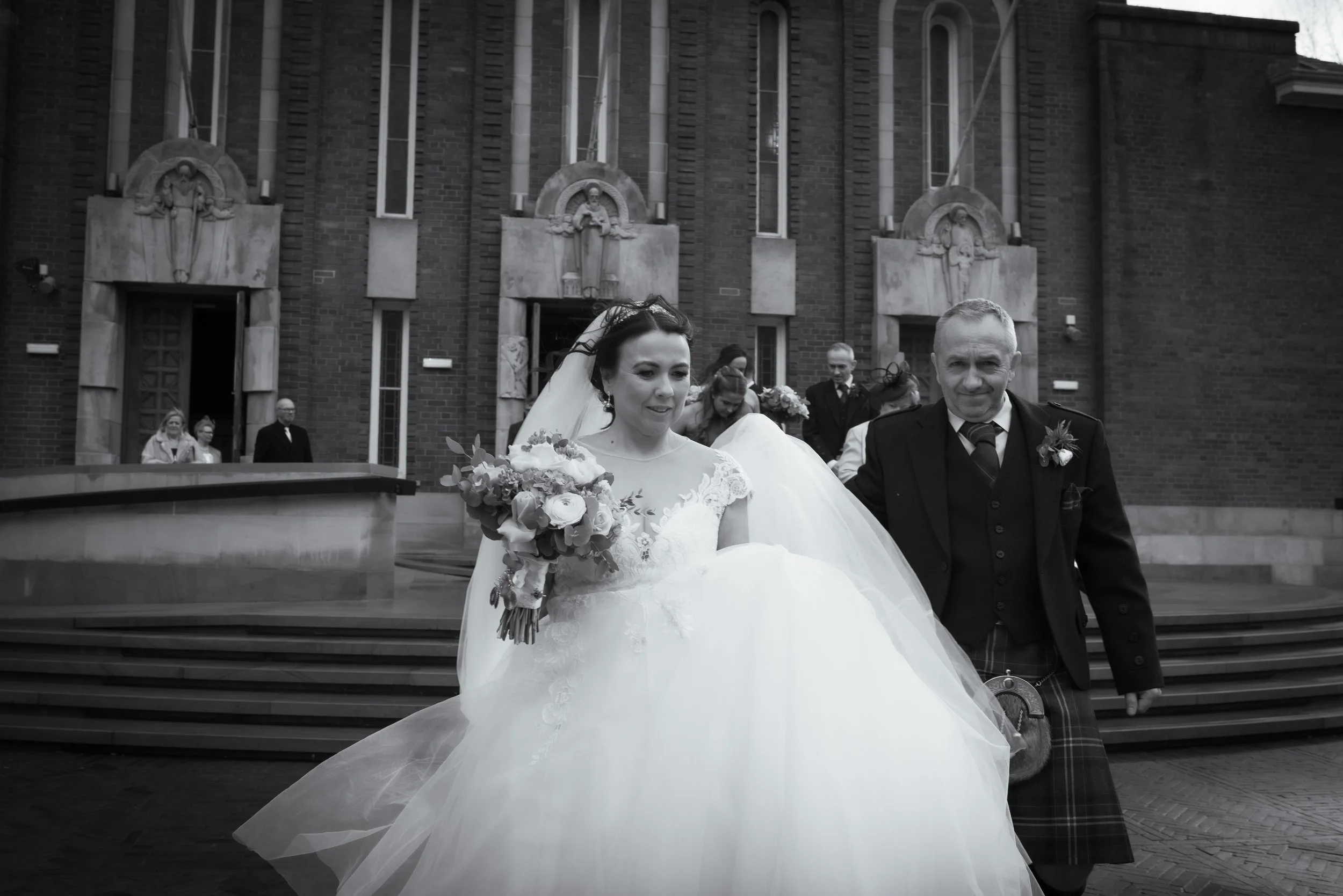 Bride leaving her wedding ceremony with her father outside the church