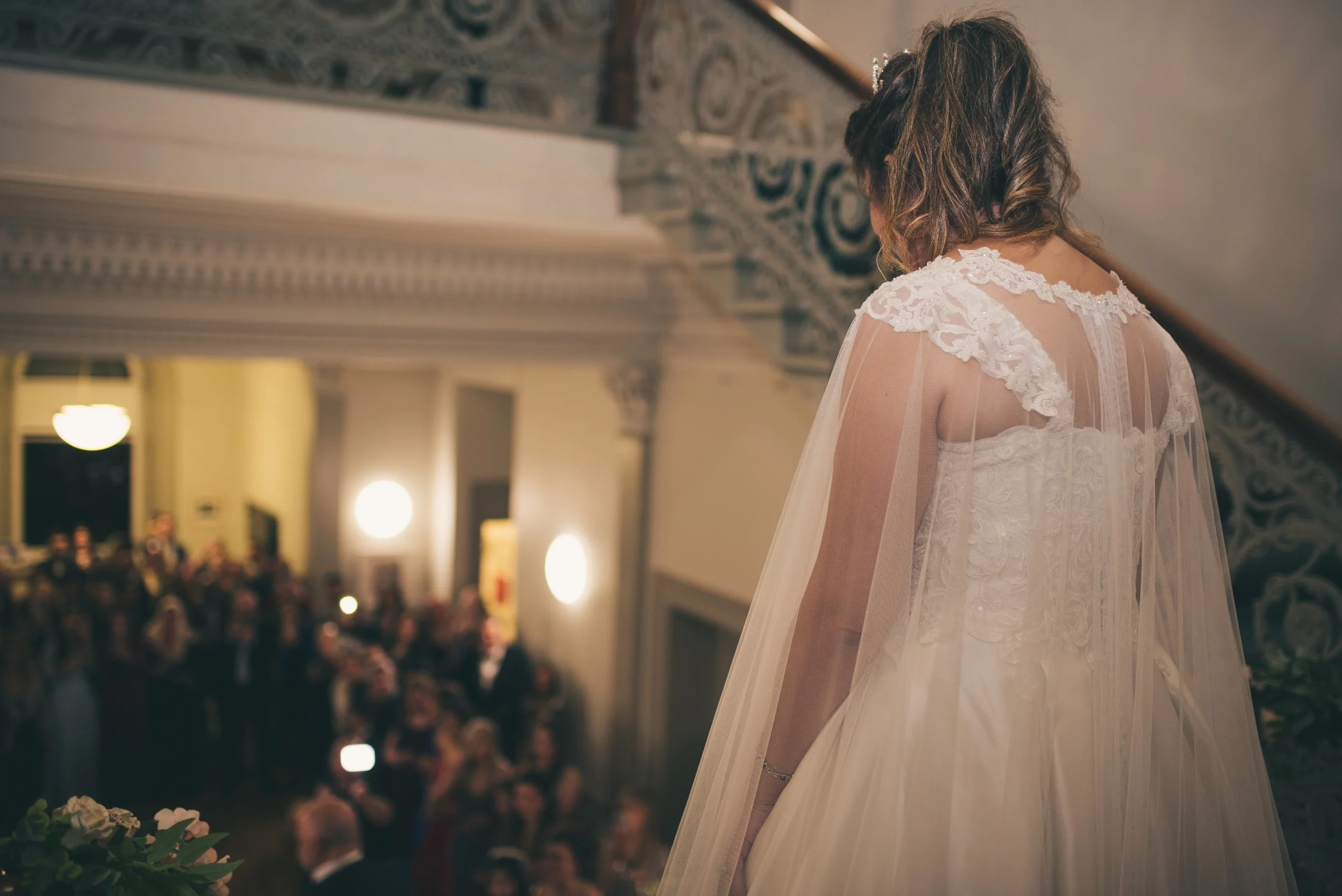 Bride looking over the wedding reception from a balcony