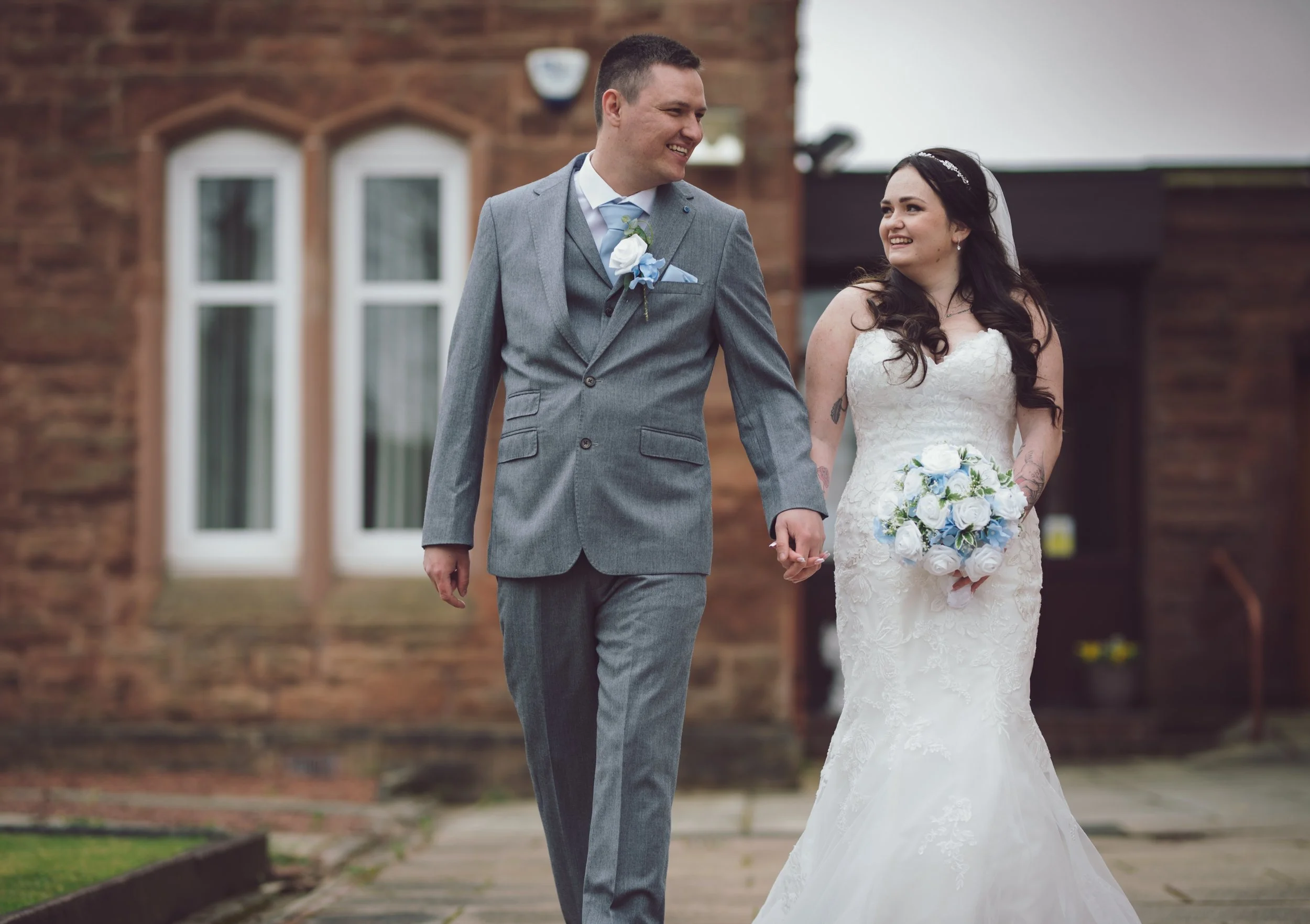 Newlywed couple walking hand in hand outside their wedding venue