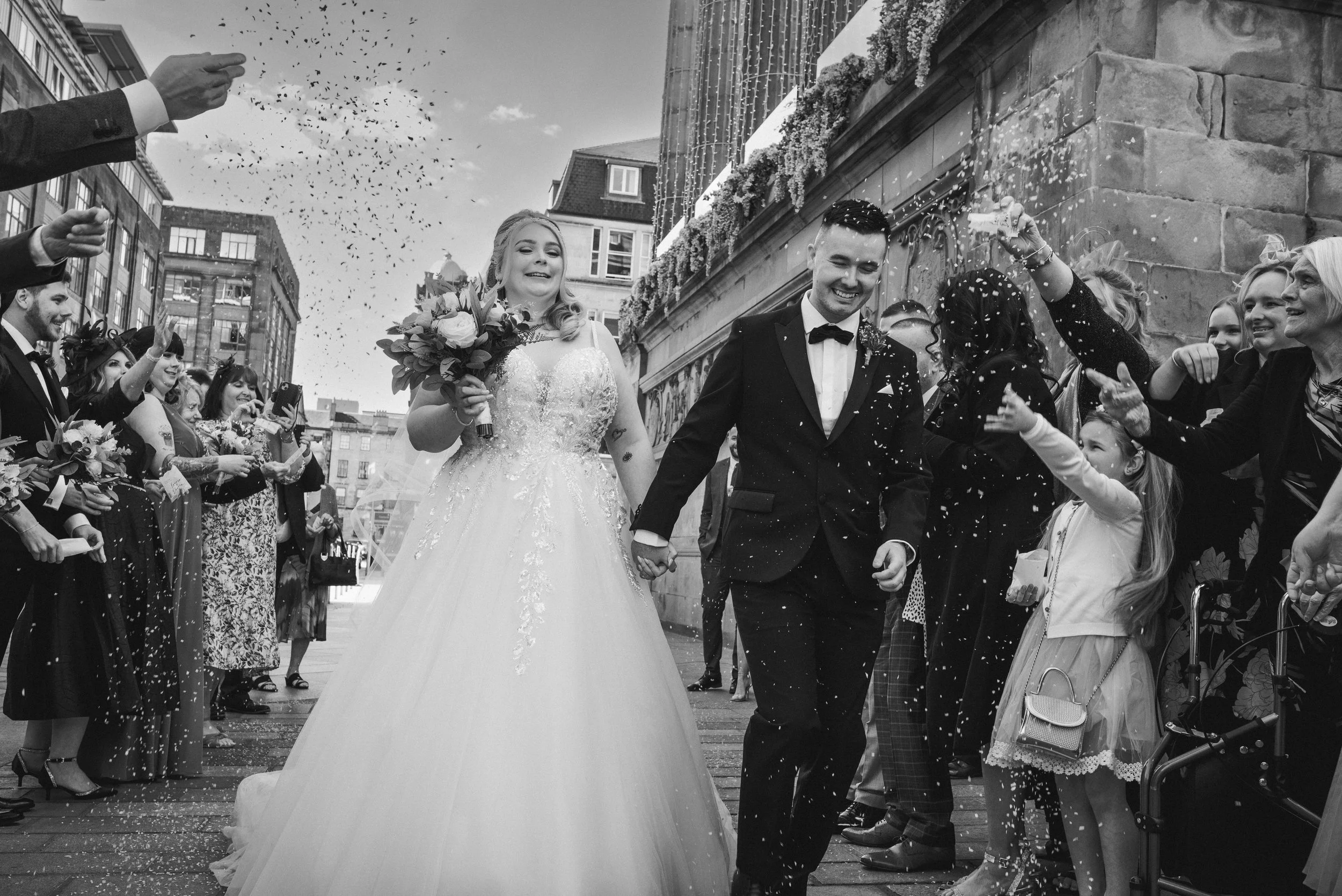 Newlyweds leaving Citation in Glasgow surrounded by cheering wedding guests and confetti
