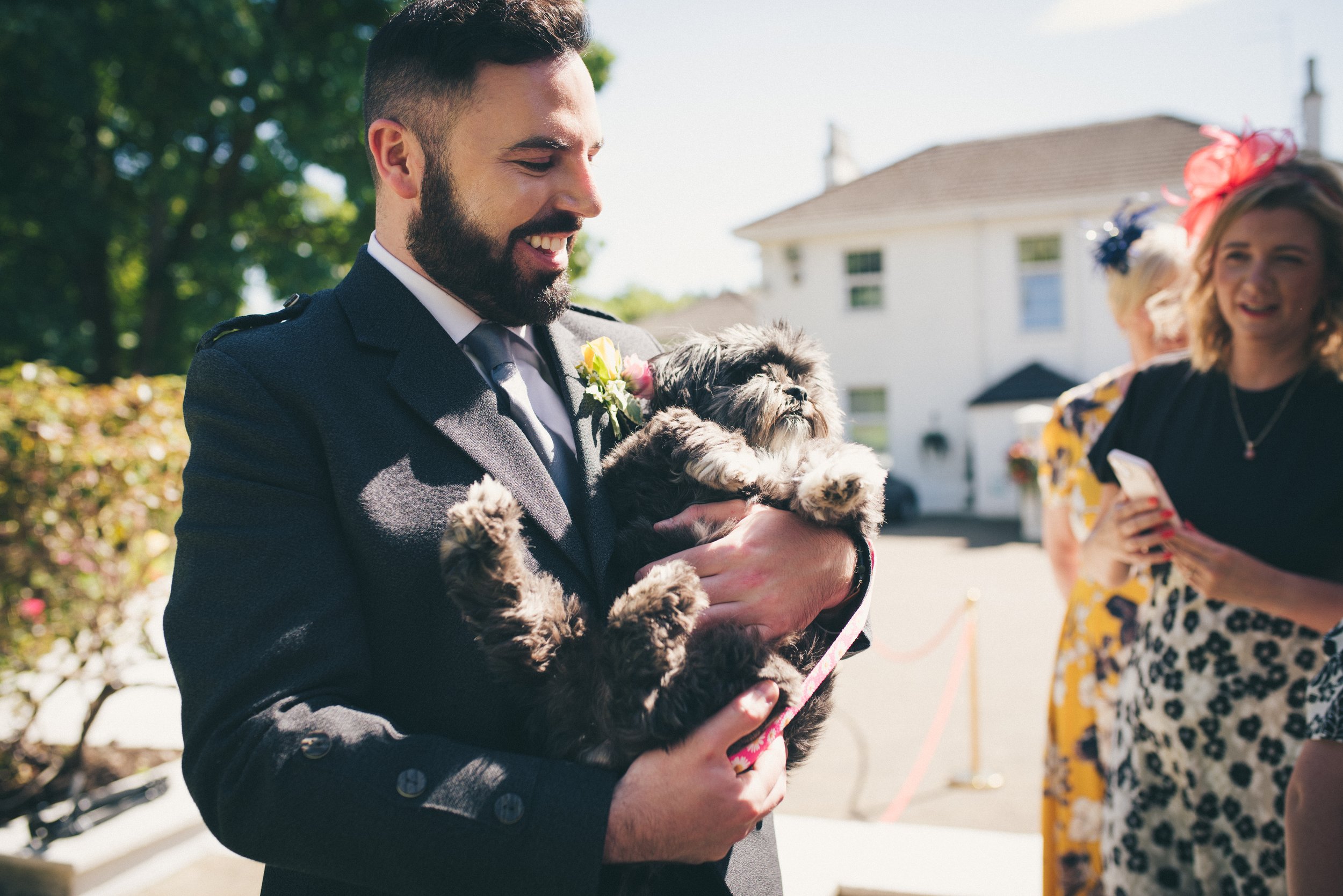 Groomsman holding the couple's dog outside their wedding venue