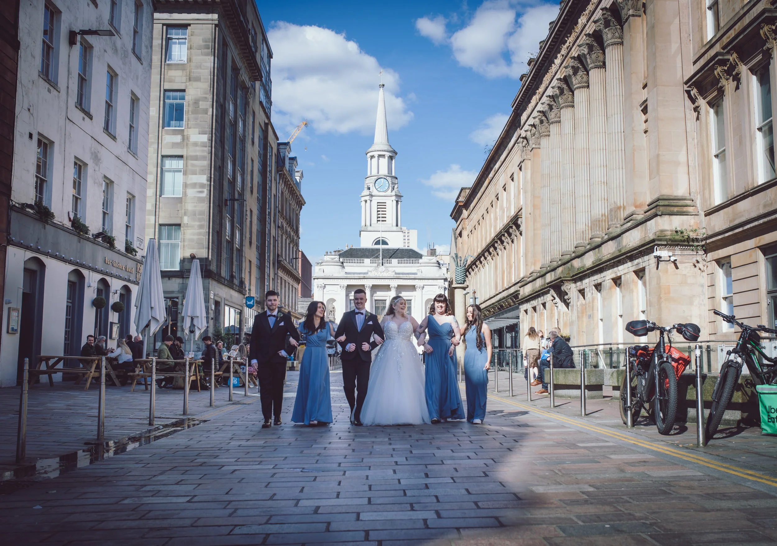 Bride and groom walking through Glasgow city centre with their wedding party