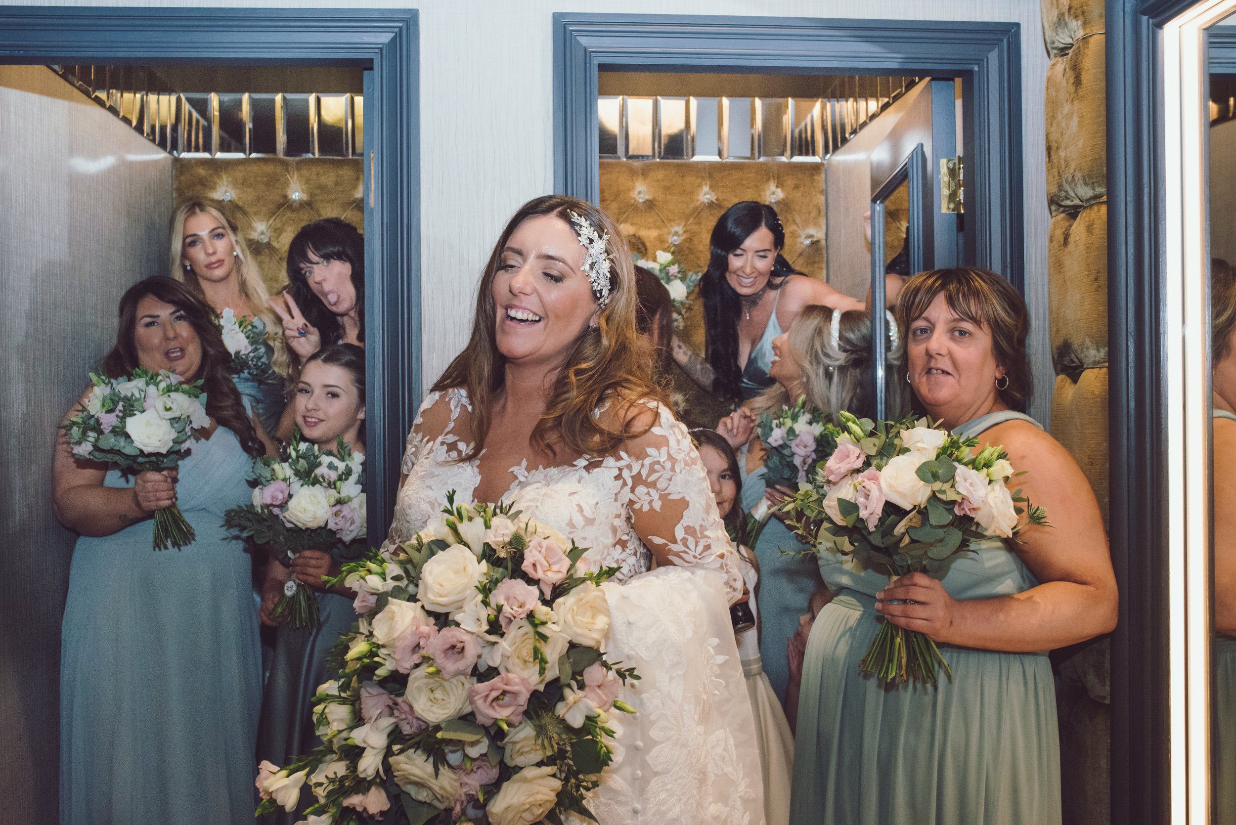 Bride laughing with her bridesmaids as they walk through the wedding venue