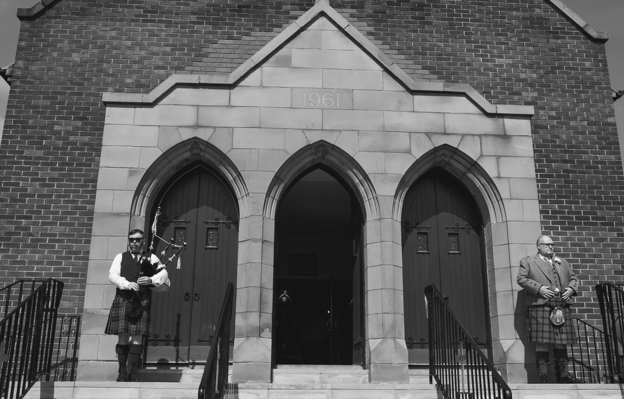 Church exterior with pipers welcoming guests to a Scottish wedding