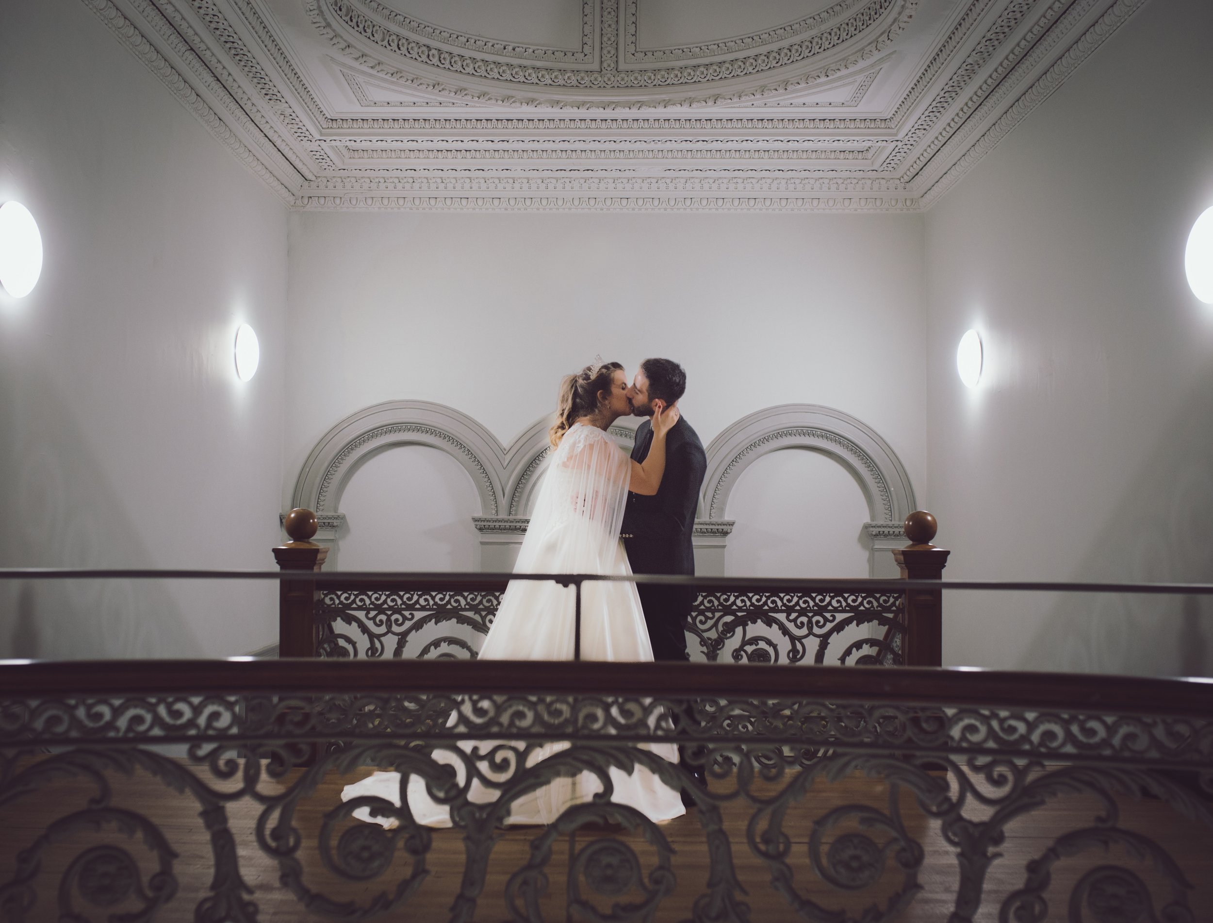 Bride and groom sharing a kiss on a wedding venue balcony
