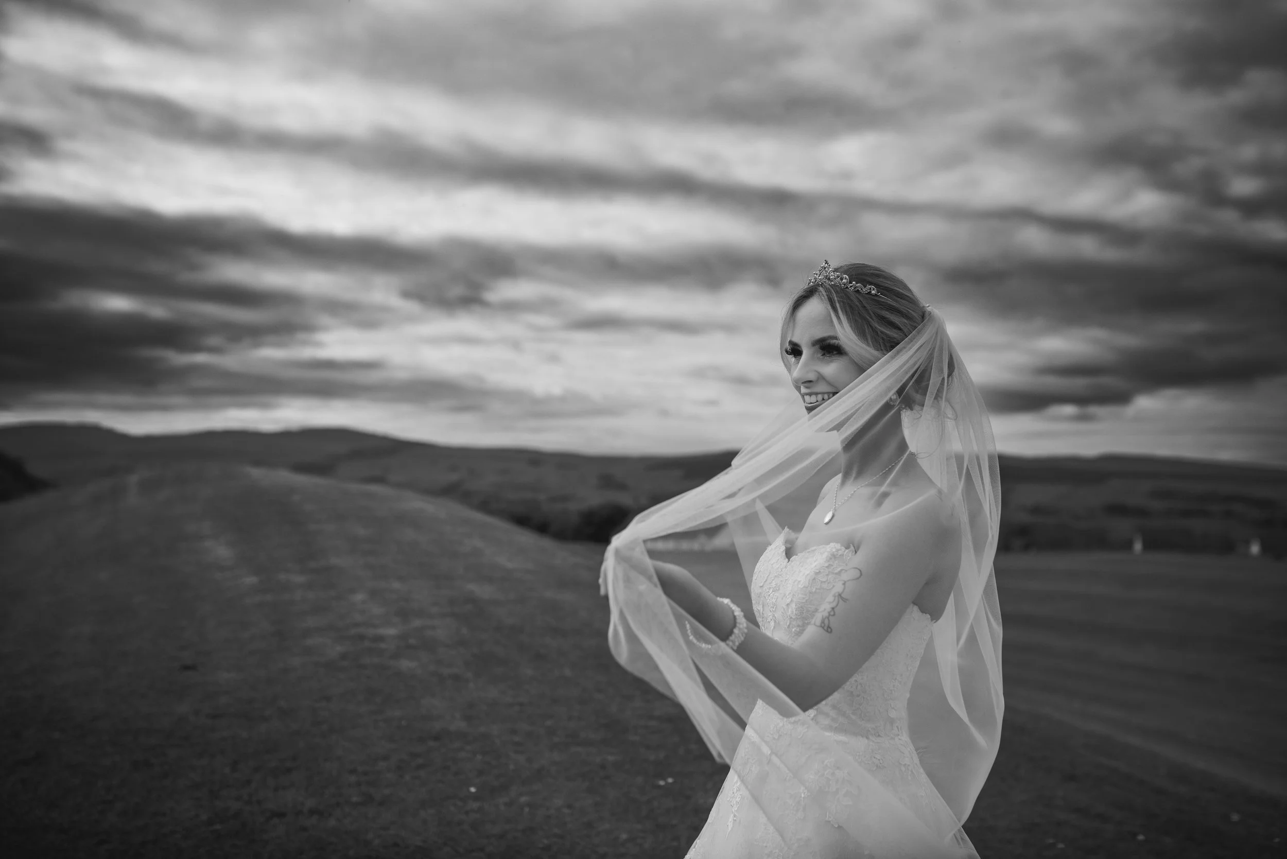 Black and white bridal portrait with the bride's veil flowing in the Scottish landscape