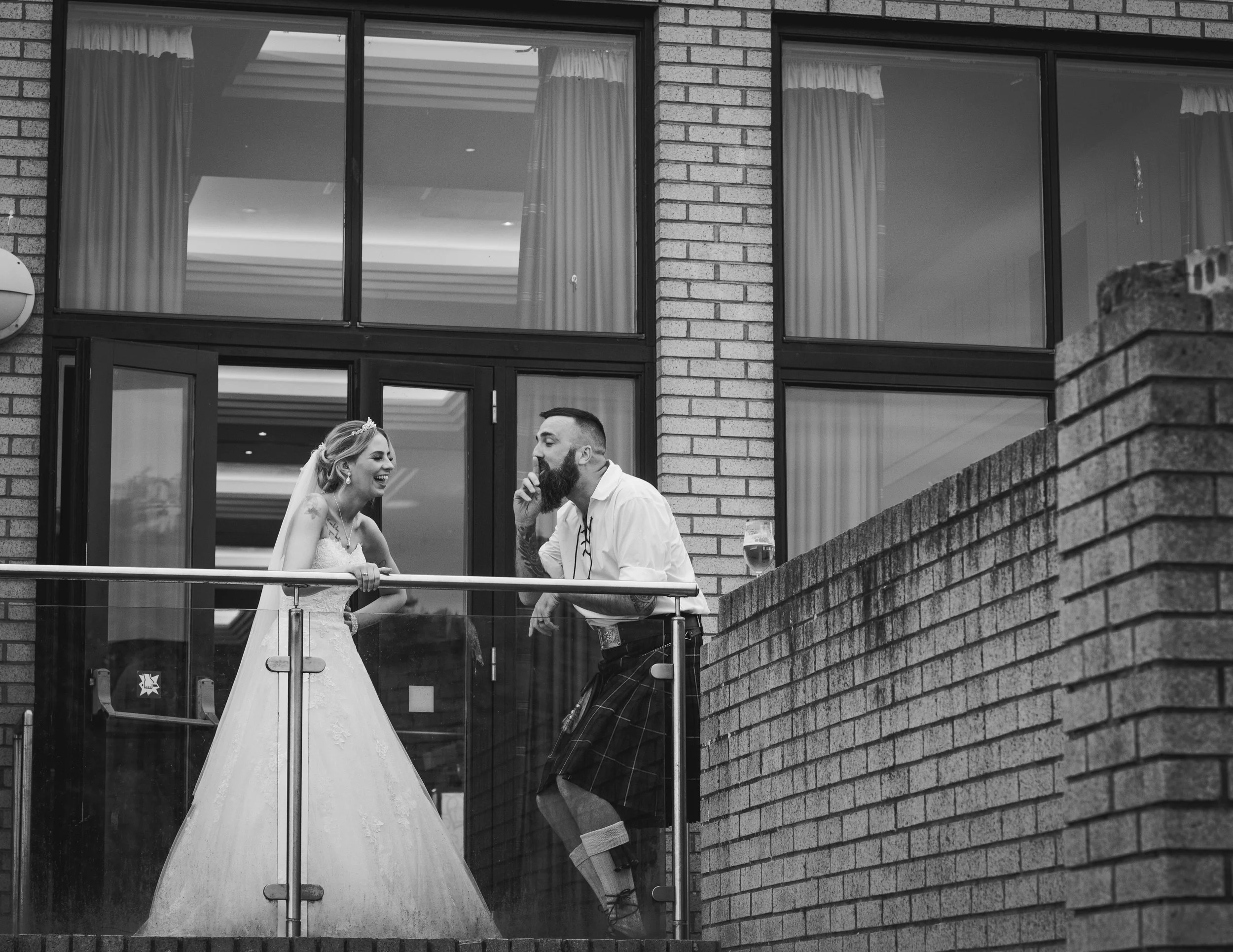 Bride laughing with a wedding guest on the balcony during the evening reception