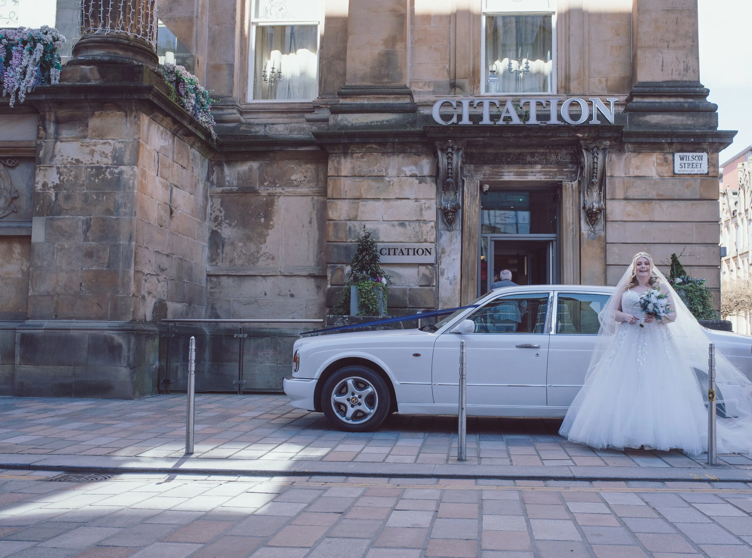 Bride arriving outside Citation wedding venue in Glasgow in a classic white wedding car