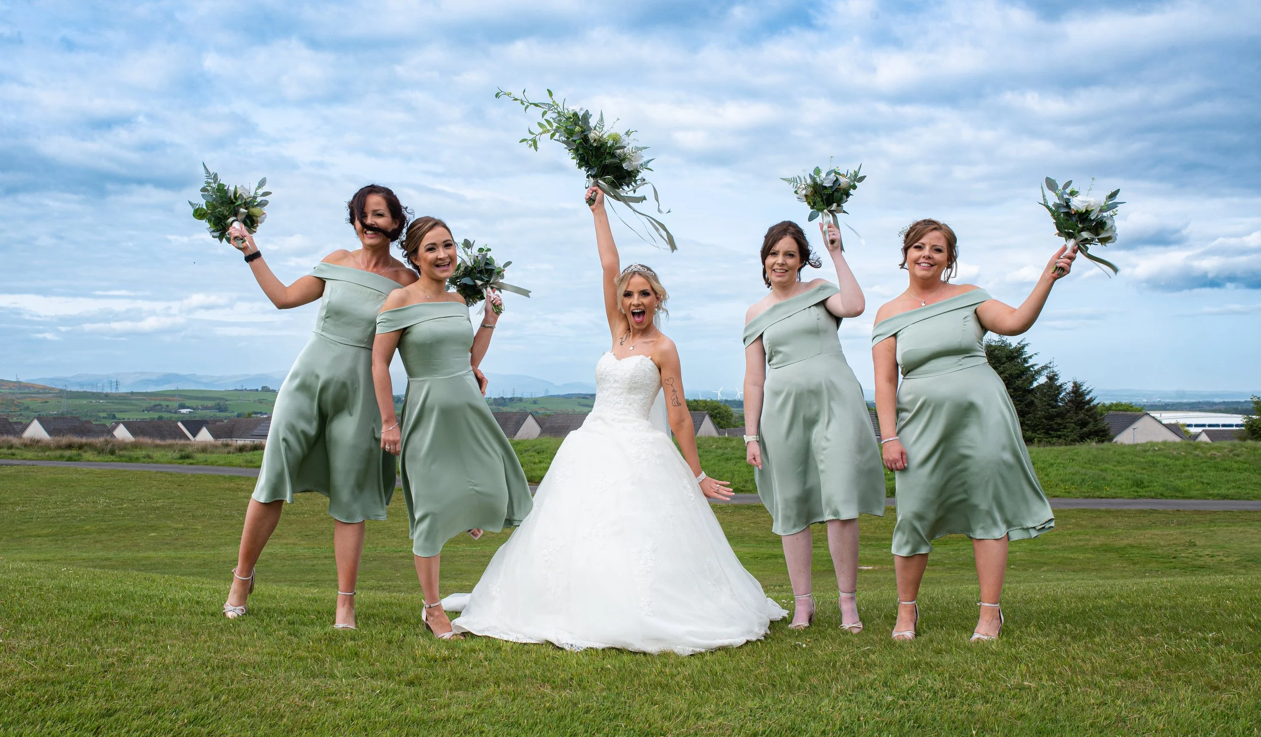 Bride celebrating with her bridesmaids outdoors on her wedding day