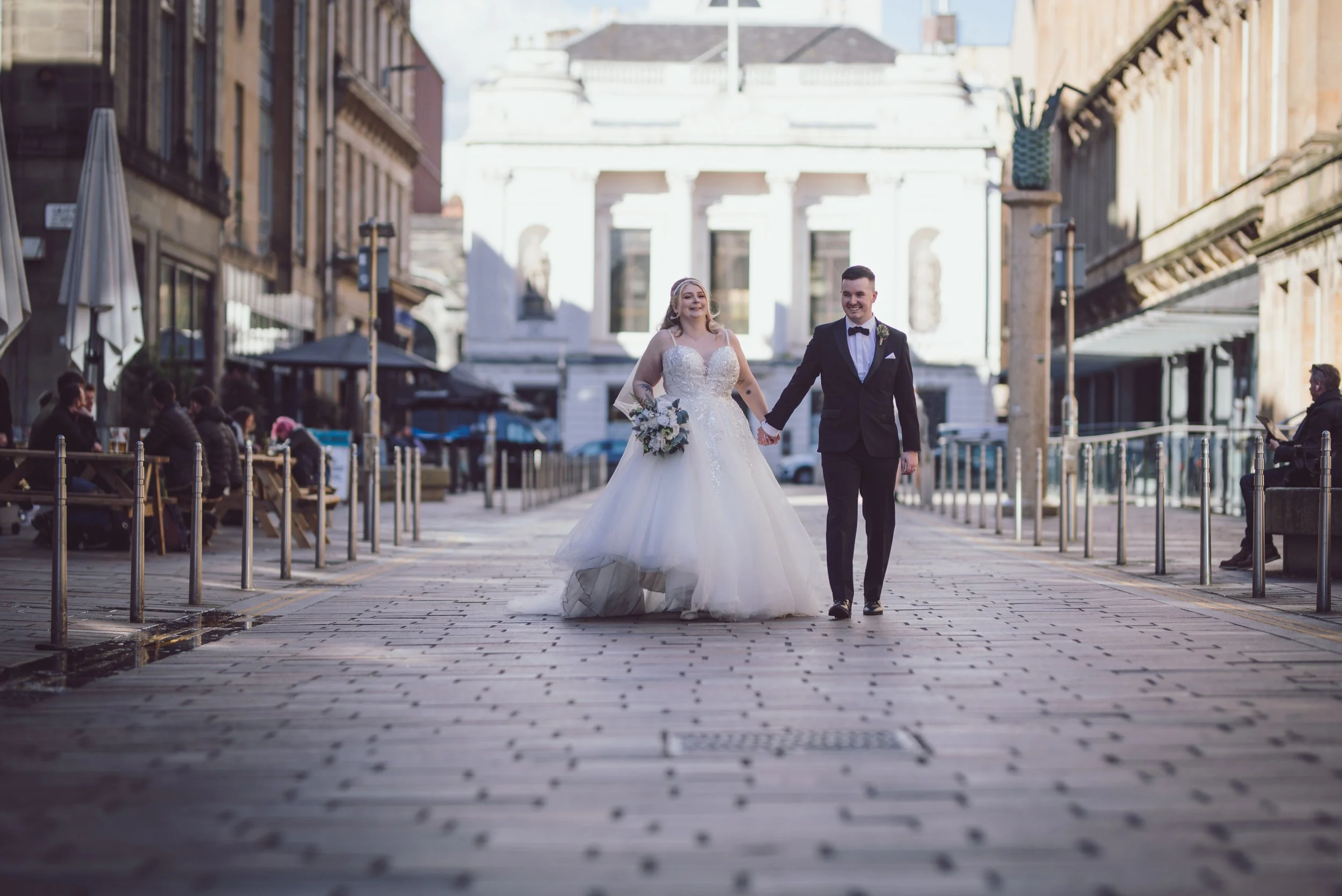 Newlywed couple walking hand in hand through Glasgow city centre