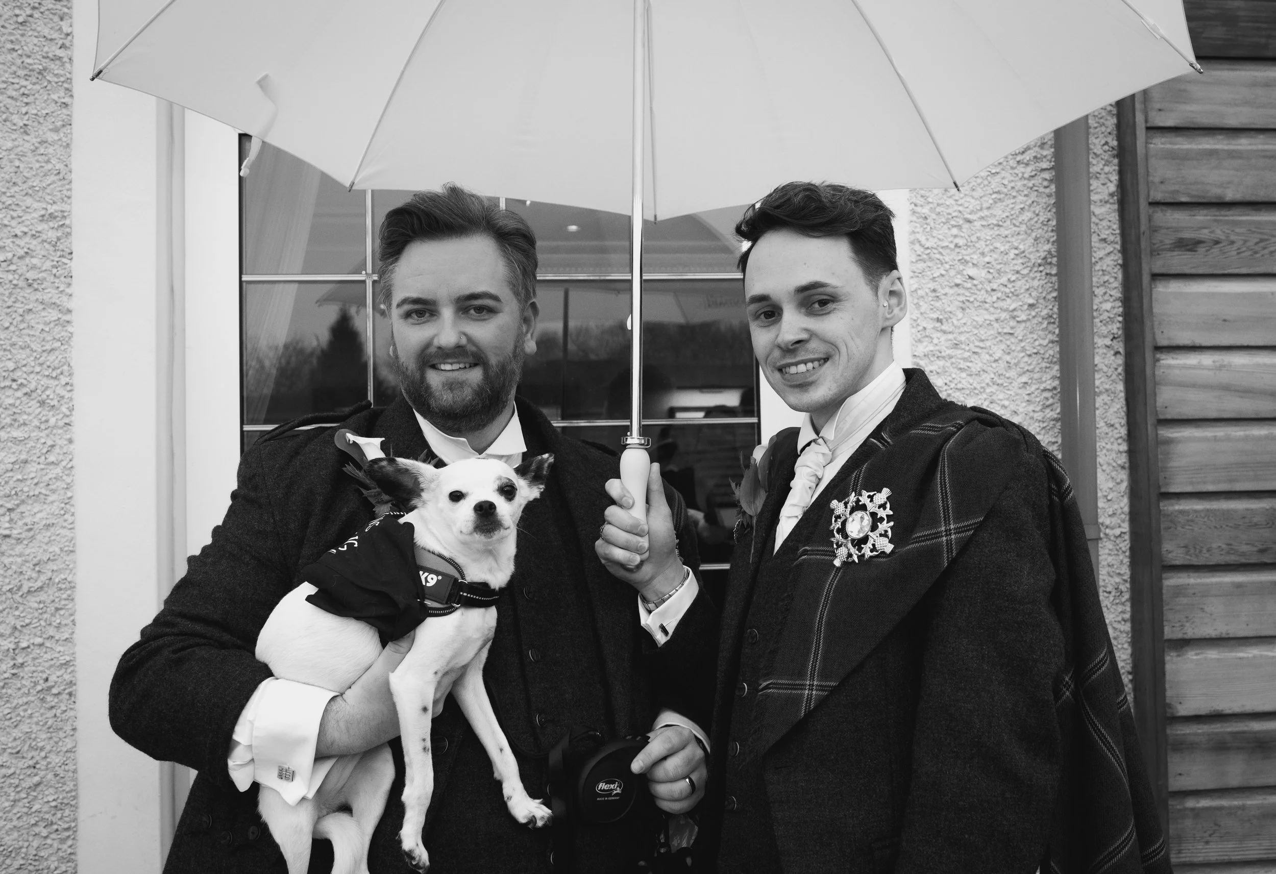 Two grooms holding their dog during their wedding day