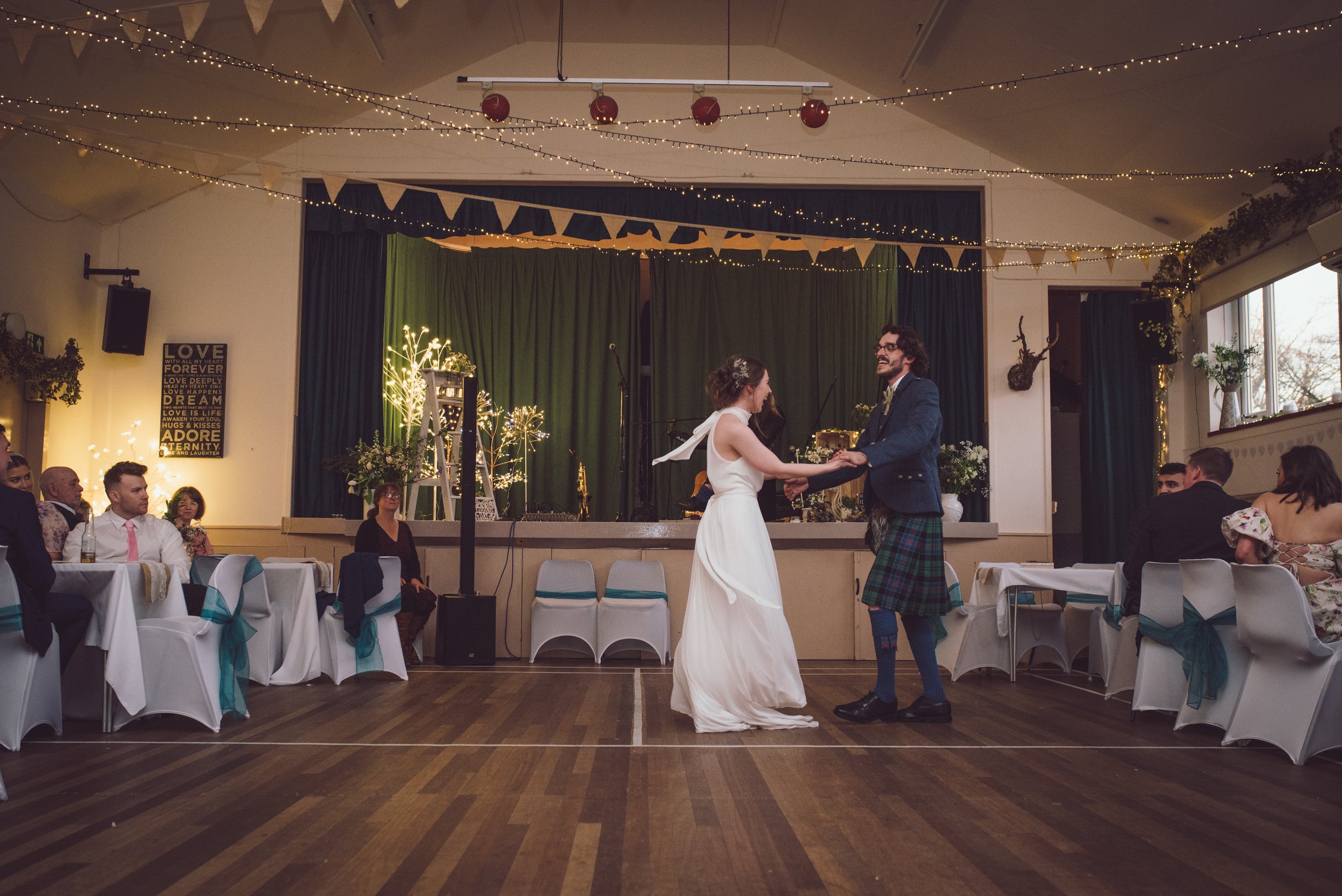 Wedding reception captured through the venue windows with guests enjoying the celebrations