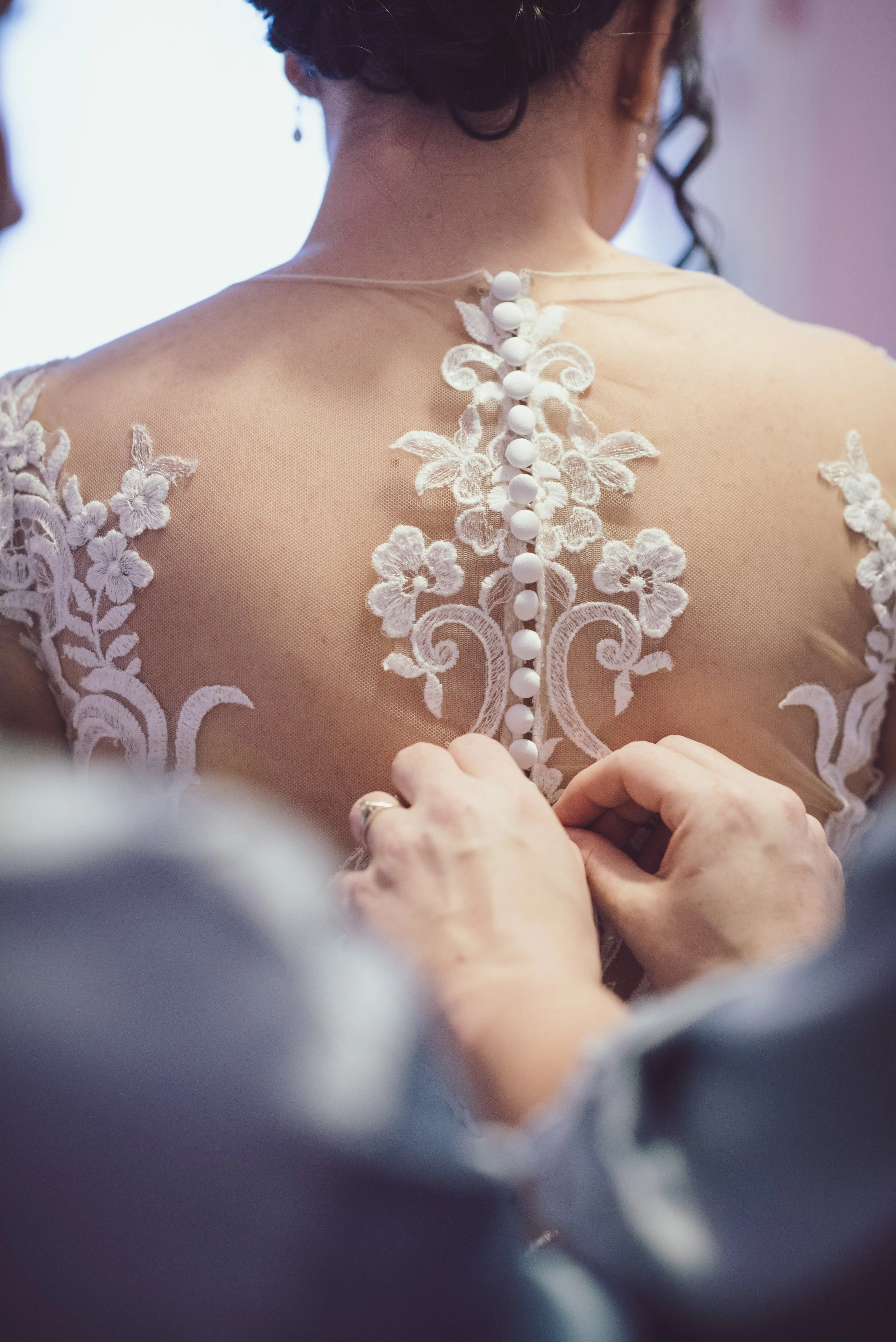 Bride having the buttons fastened on the back of her wedding dress