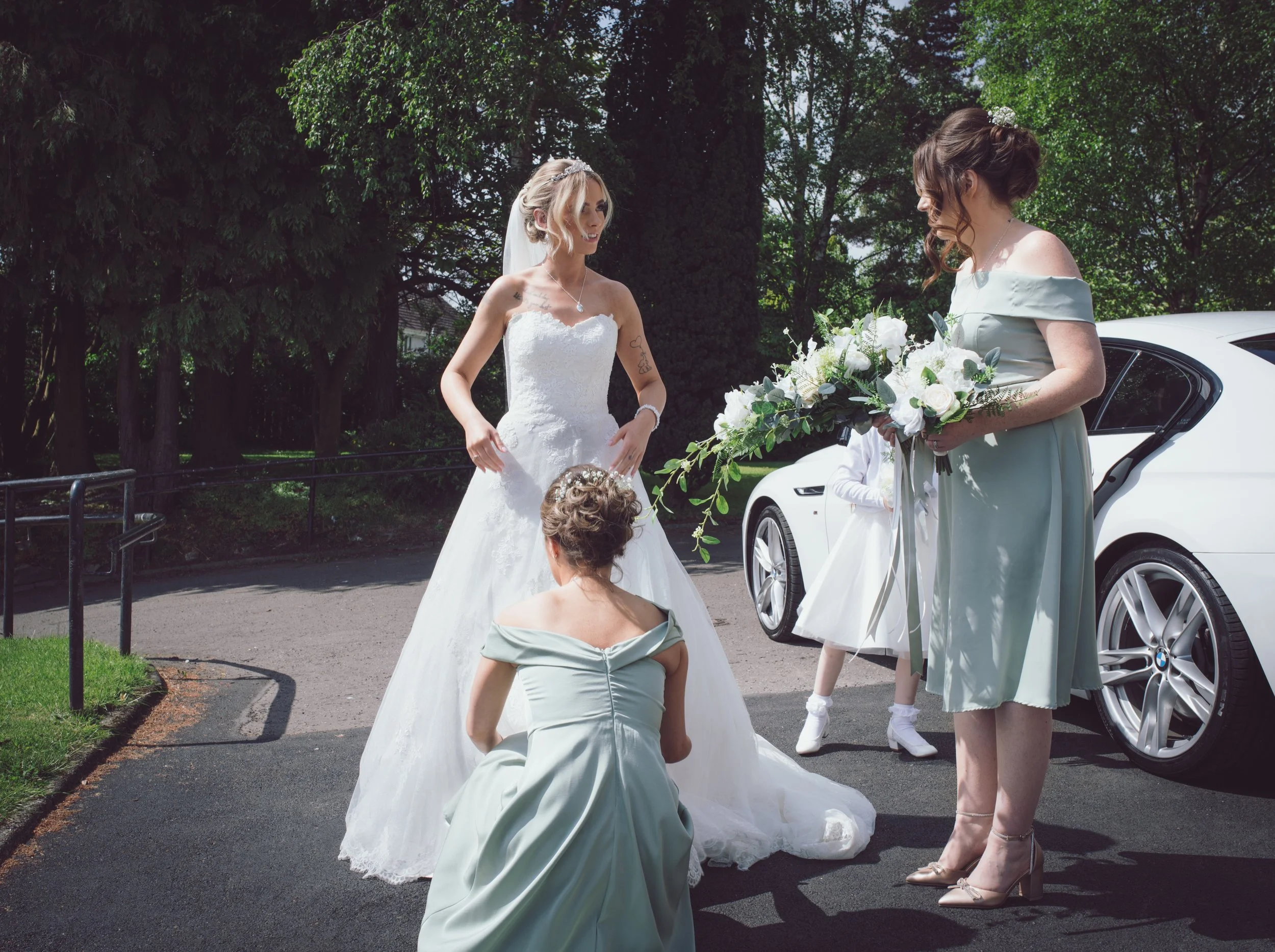 Bride getting ready outside the church with her bridesmaids and wedding bouquet