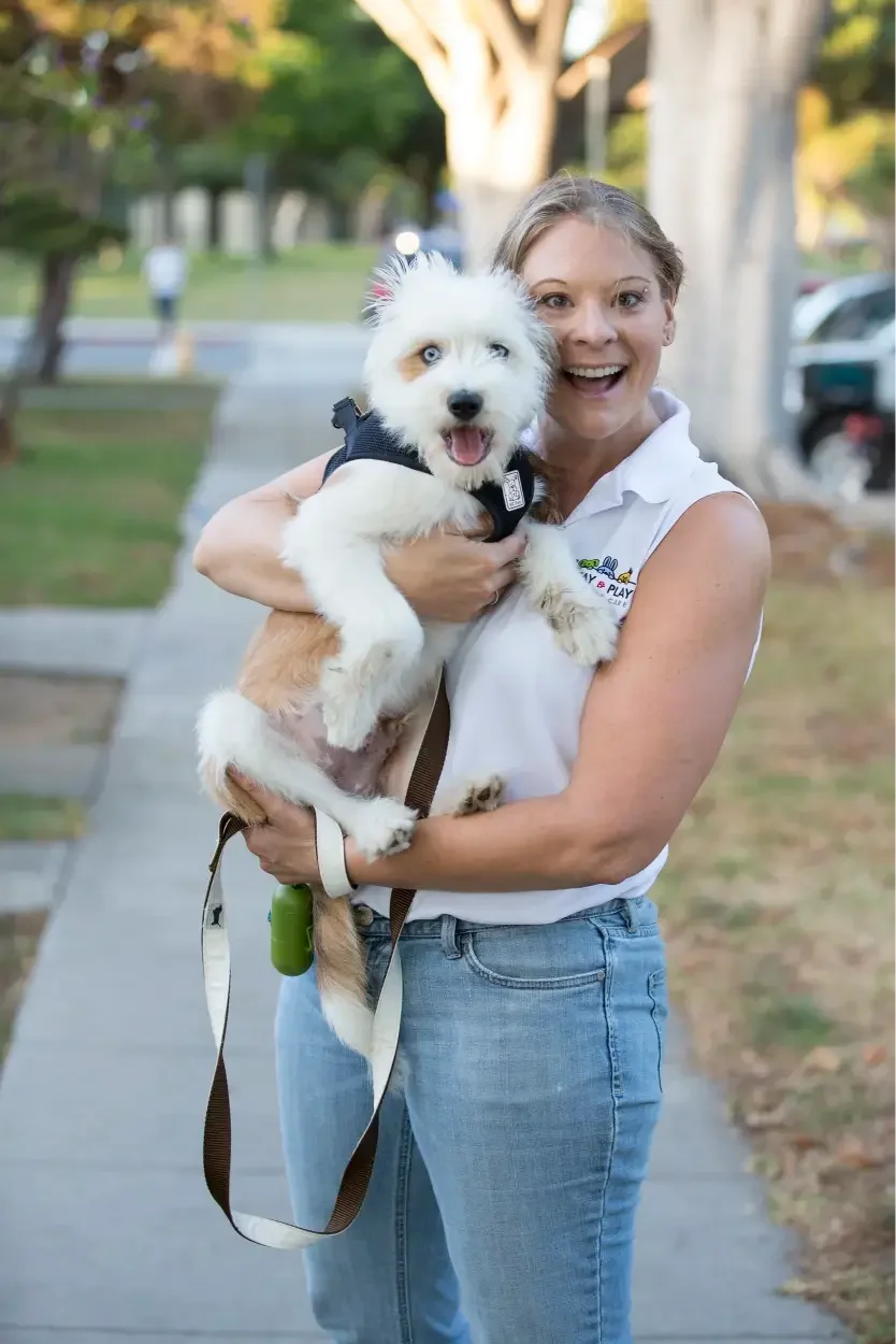 Happy woman holding a white dog with blue eyes outdoors