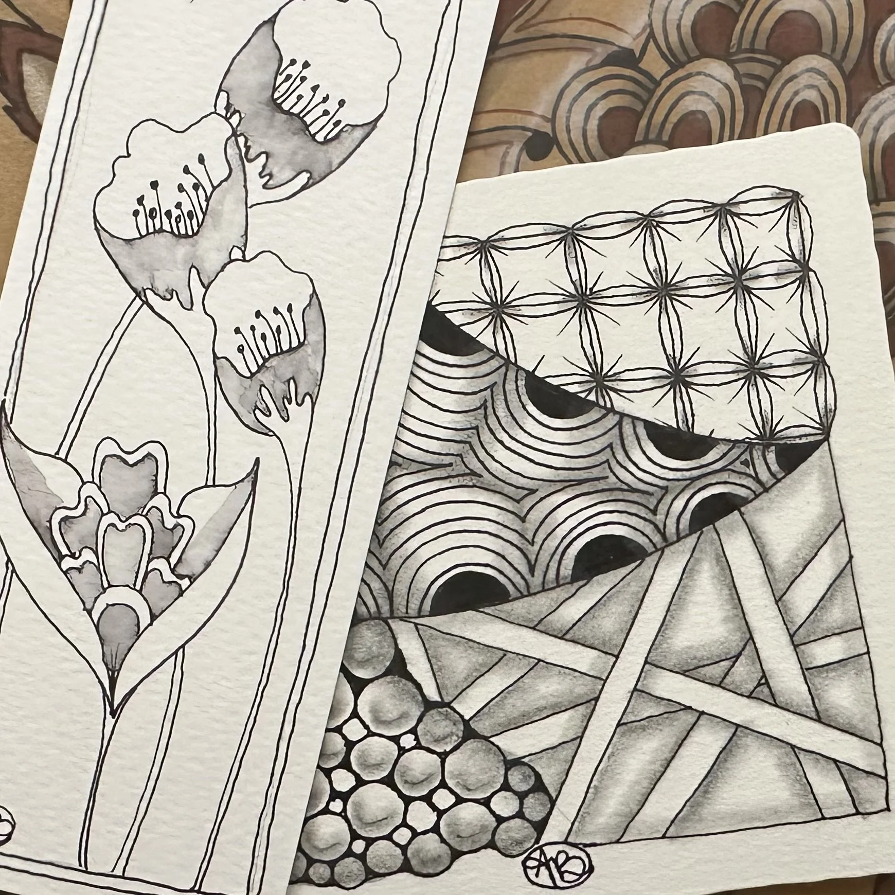 Two black-and-white ink drawings featuring patterns: one with floral designs and another with geometric shapes.