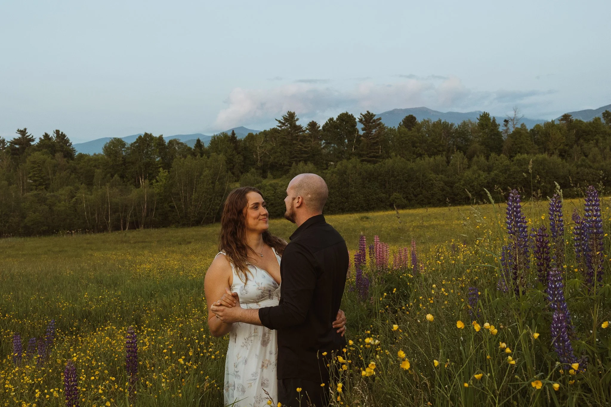 Mountain elopement in the White Mountains featuring a couple exploring lupines and wildflower fields and open skies