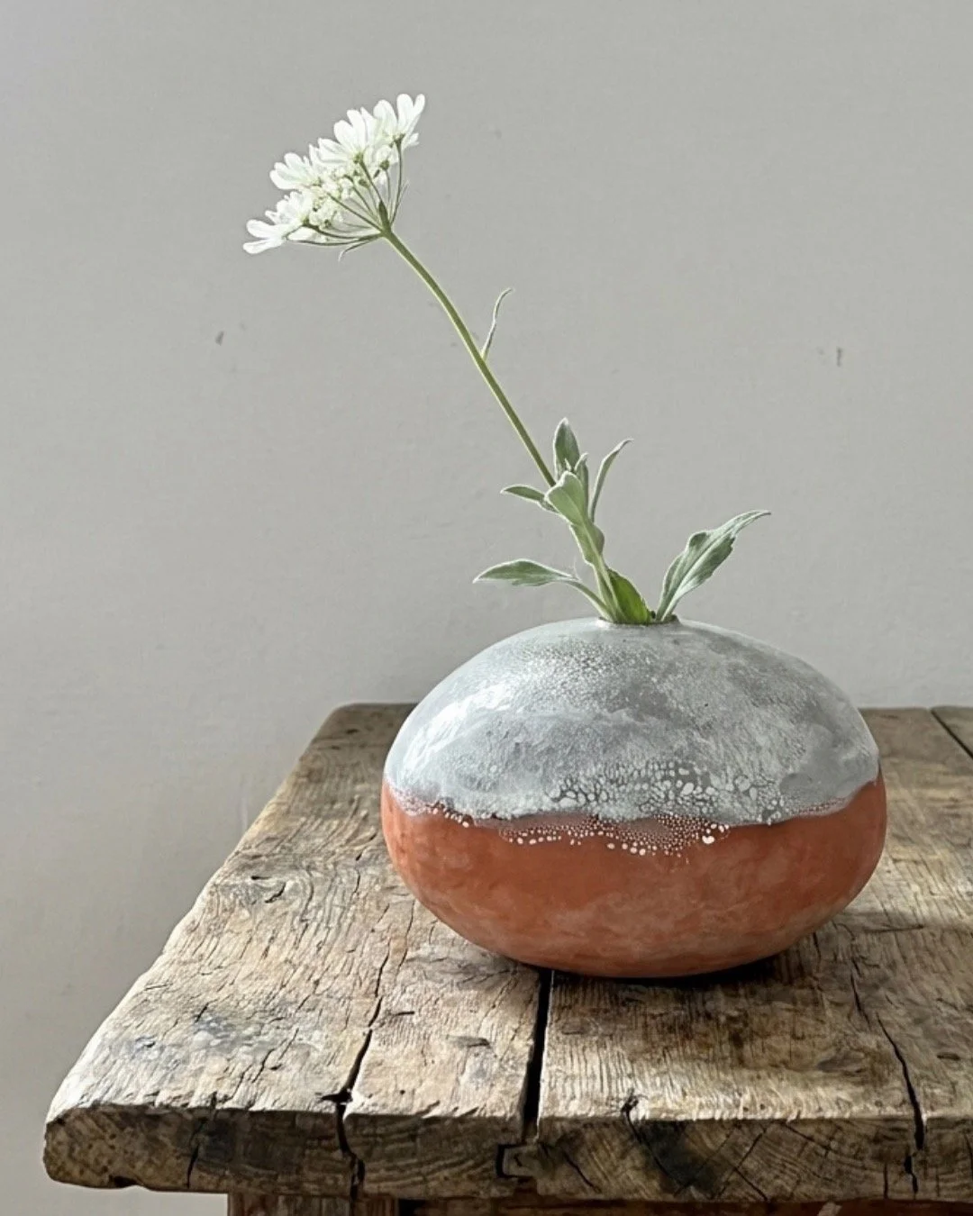 Wo warmes Terracotta auf zarten Fr&uuml;hling trifft. 
Diese runde Vase tr&auml;gt zwei Welten in sich &mdash; unten das warme, lebendige Rot, oben eine zarte, strukturierte Glasur wie ein erster Morgenfrost. Und dazwischen: diese magische Grenze, wo
