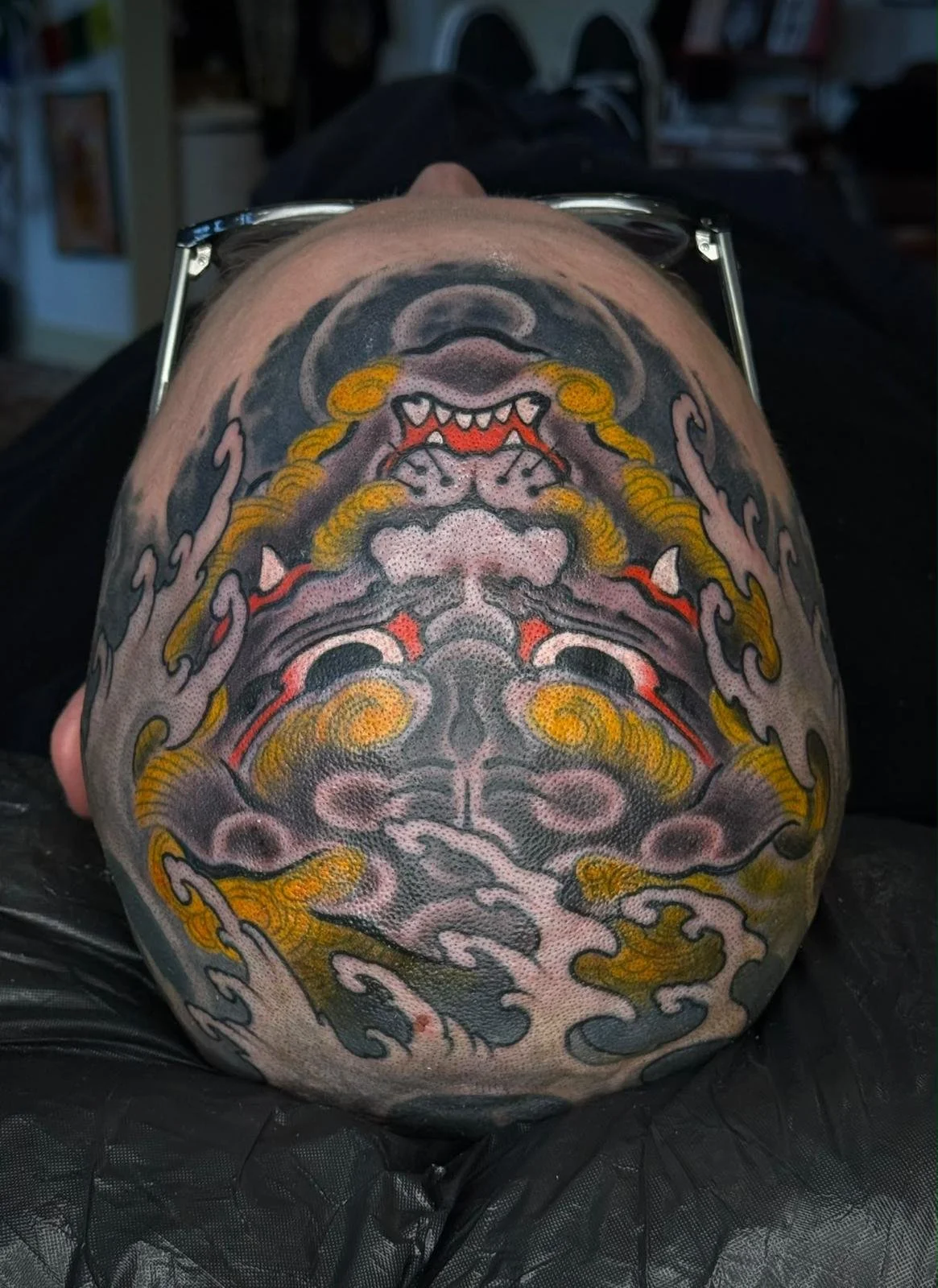 Colorful tattoo of a fierce Asian-style dragon on person's back, surrounded by swirling clouds.