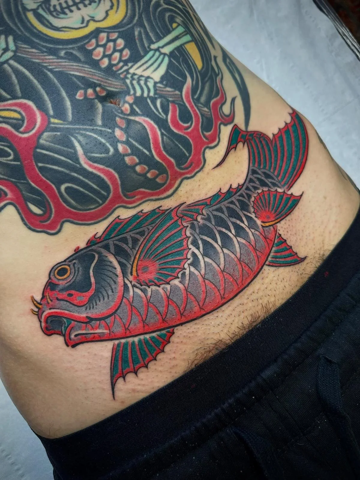A traditional Japanese style tattoo of a red and gray koi fish swimming.