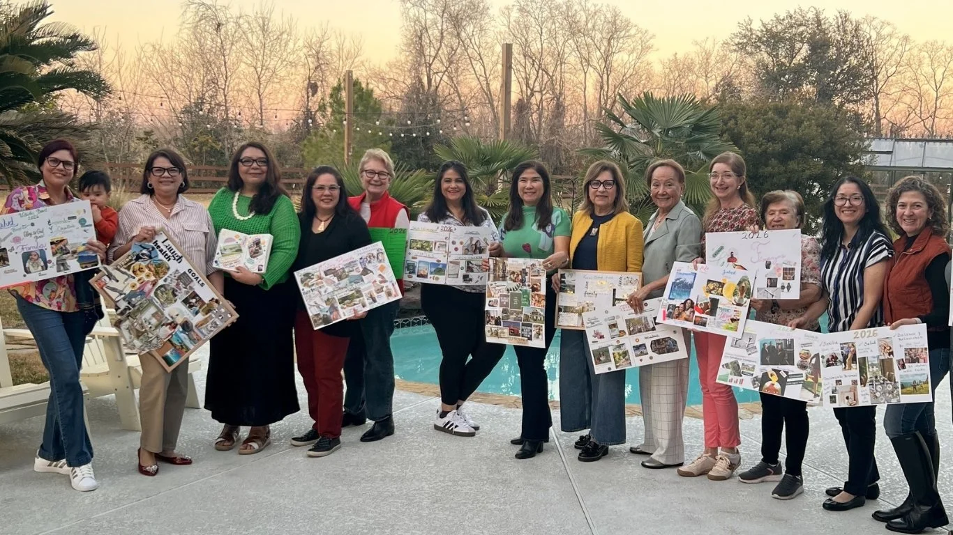 Group of women holding photo collages, standing outdoors near a pool at sunset.