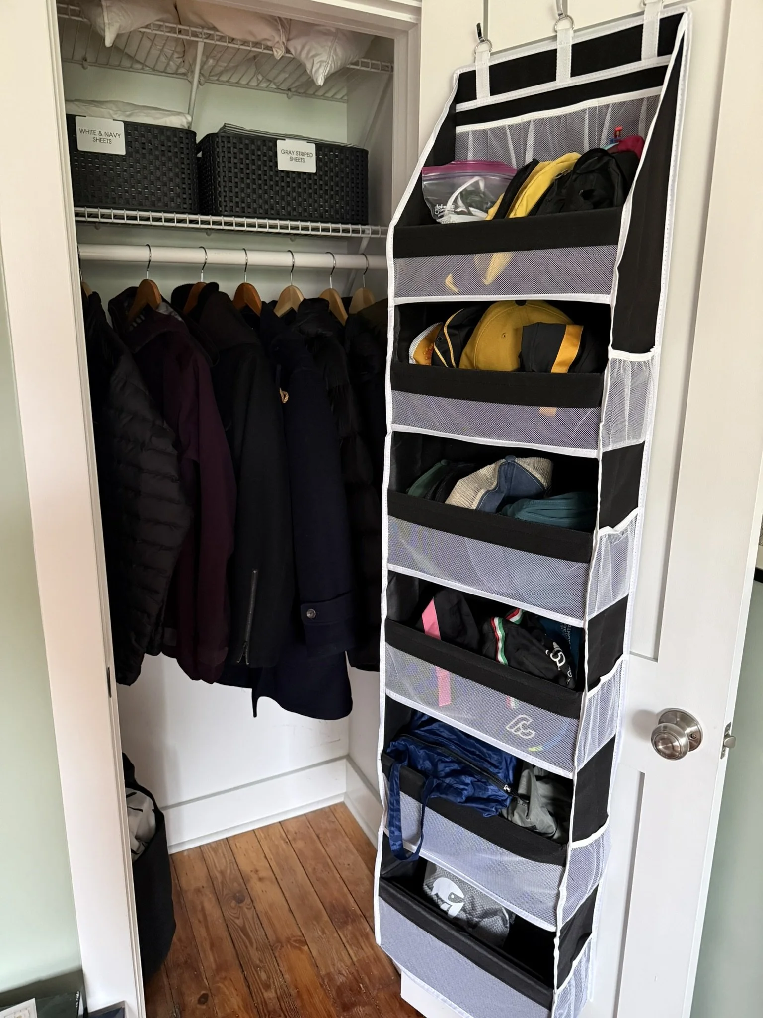guest room closet with off-season coats, an over the door organizer and sheet sets