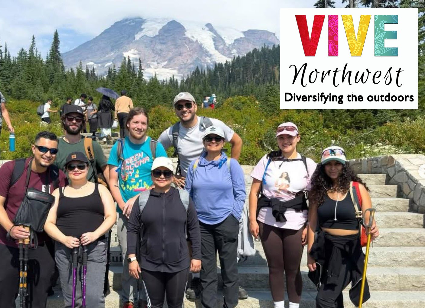A group of young adults with backpacks and trekking poles stand on the steps at the Paradise Visitor Center with Mt. Rainier in the background and the VIVE Northwest logo