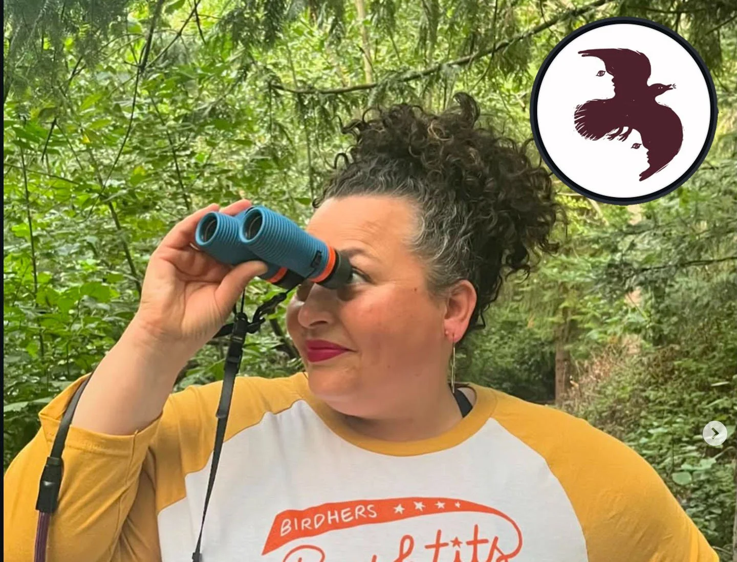 A woman in a shite and yellow shirt looking through binoculars with trees in the background