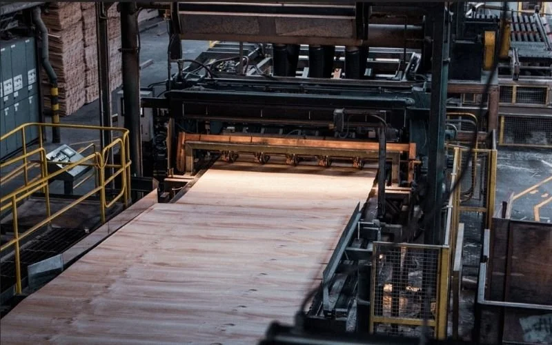 Machinery in a factory with wood going through a machine