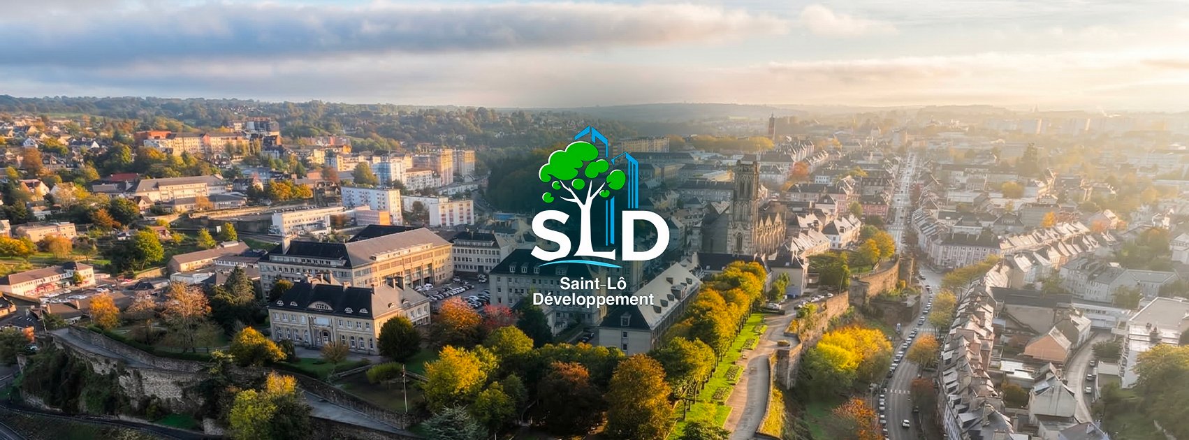 Vue aérienne d'une ville avec des bâtiments et des arbres colorés à l'automne, et un logo avec un arbre et des bâtiments au centre.