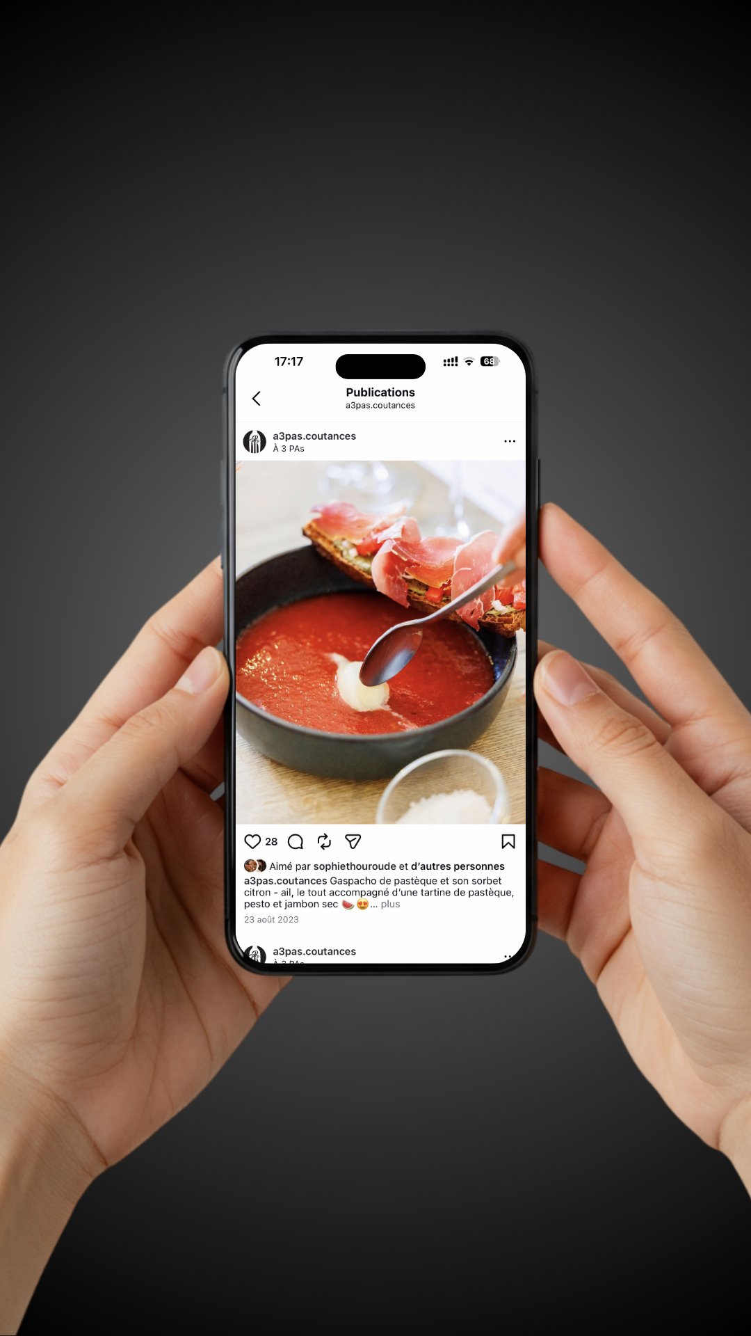 Photo d'un téléphone portable tenu par deux mains, montrant une publication Instagram d'une soupe à la tomate avec une tartine de pâté, jambon sec et sorbet citron.