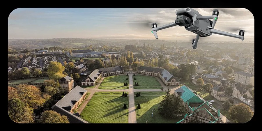 Un drone vole au-dessus d'un jardin avec des bâtiments historiques et une ville en arrière-plan.