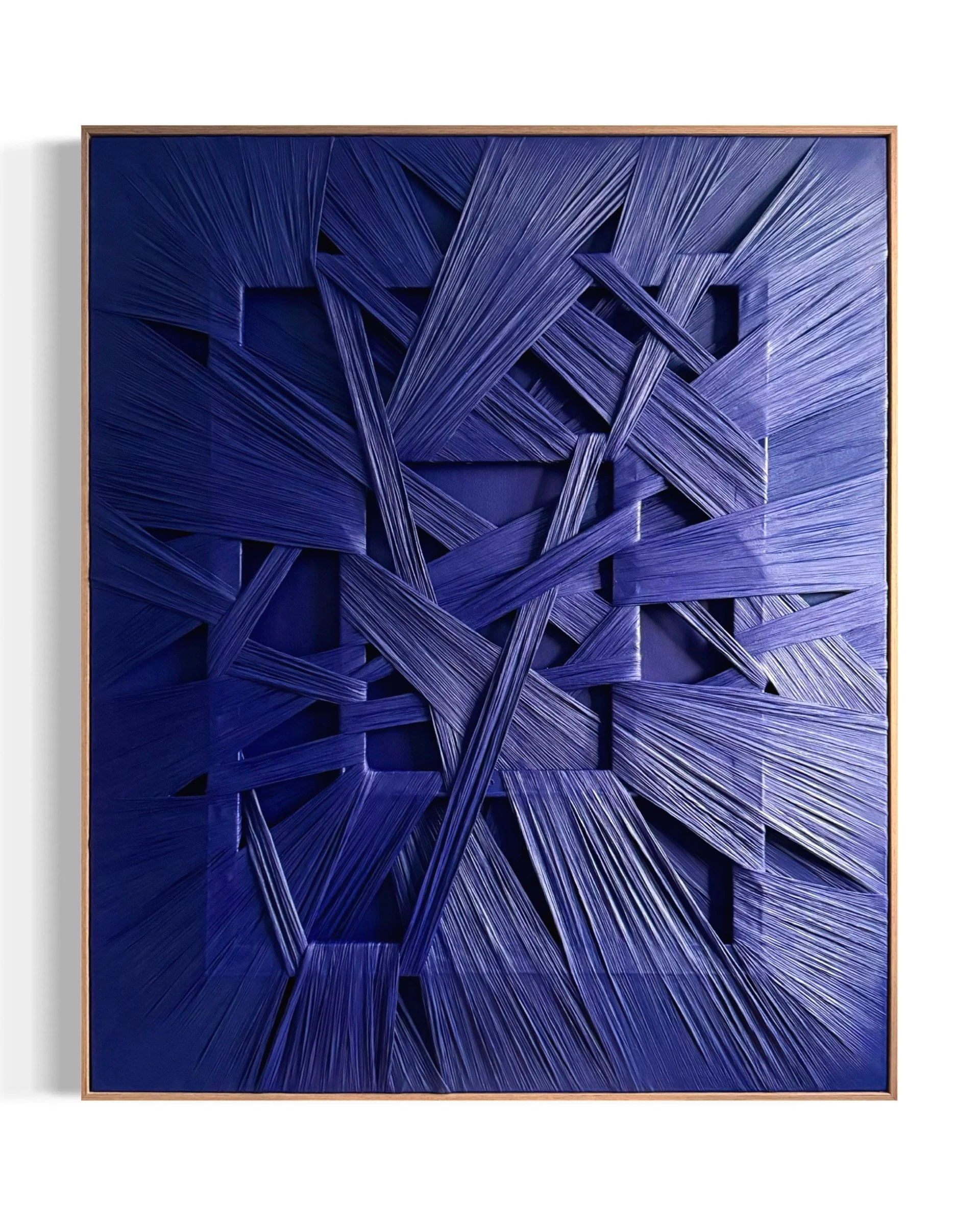 An abstract artwork with layered blue strips creating a textured, geometric pattern inside a wooden frame.