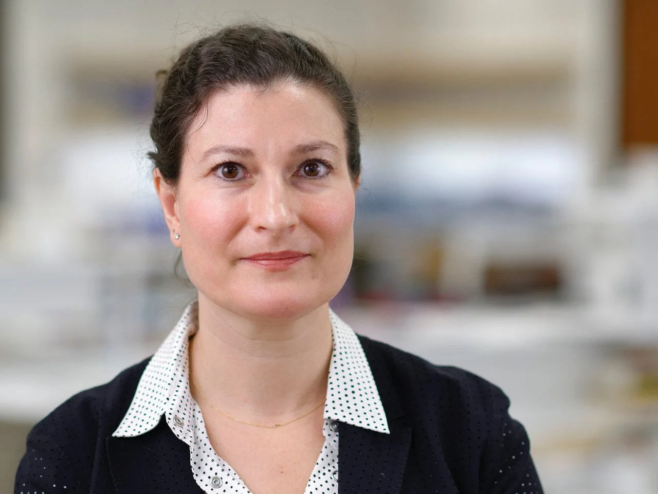 Portrait photo of Laura Forlano. Laura stands in front a blurred background, smiling.
