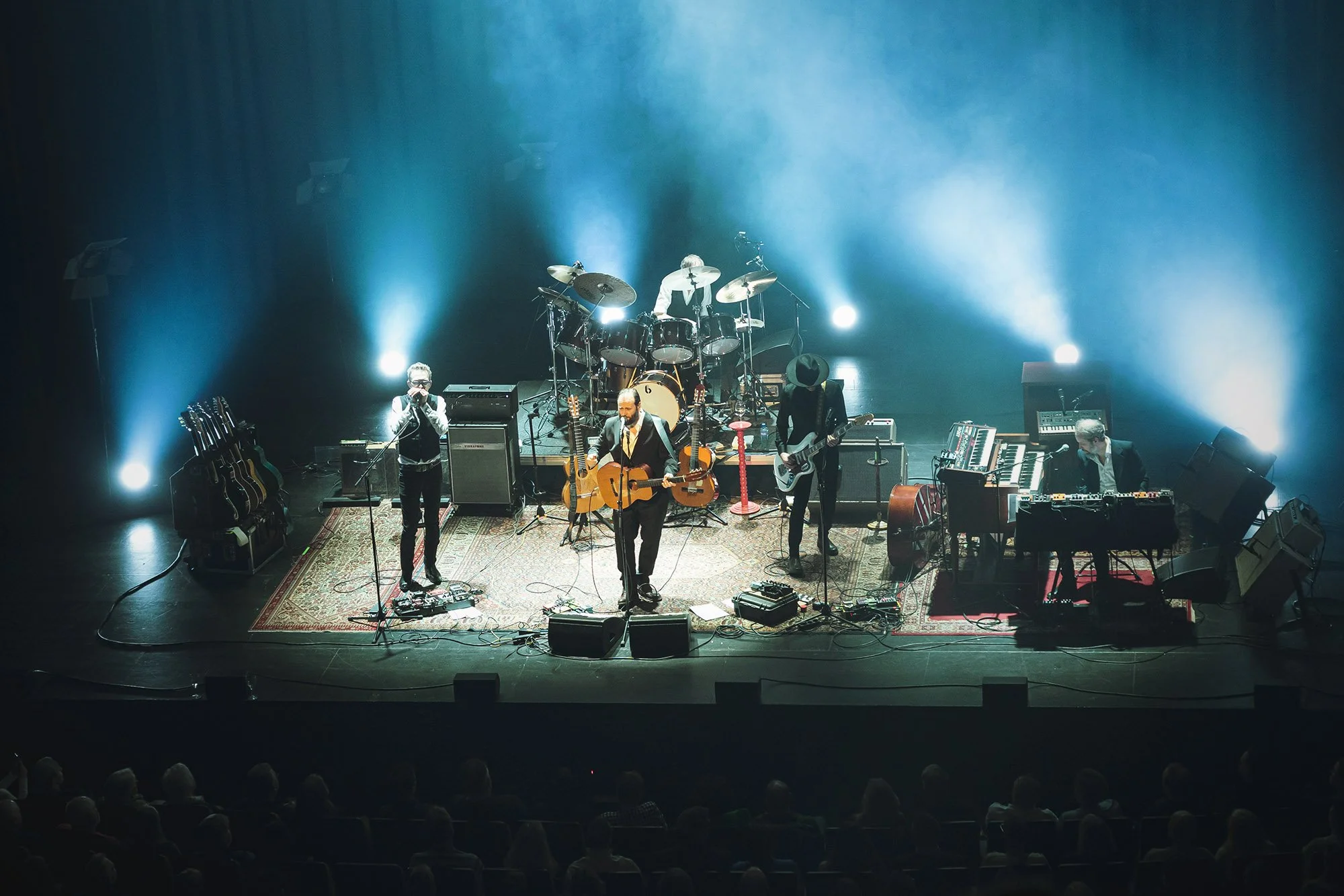 Stein Torleif Bjella står på scenen i Olavshallen med fullt band bak ryggen og kassegitar i hendene.
