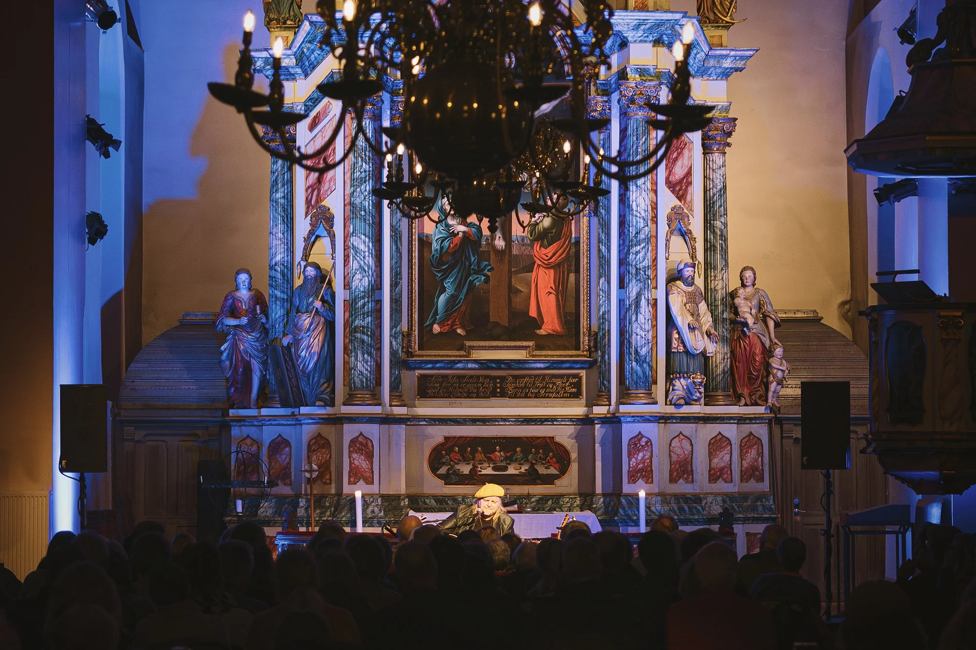 En lyskrans i taket, publikum i salen og musikk fra scenen, inne i tidløse omgivelser i Vår Frue Kirke.