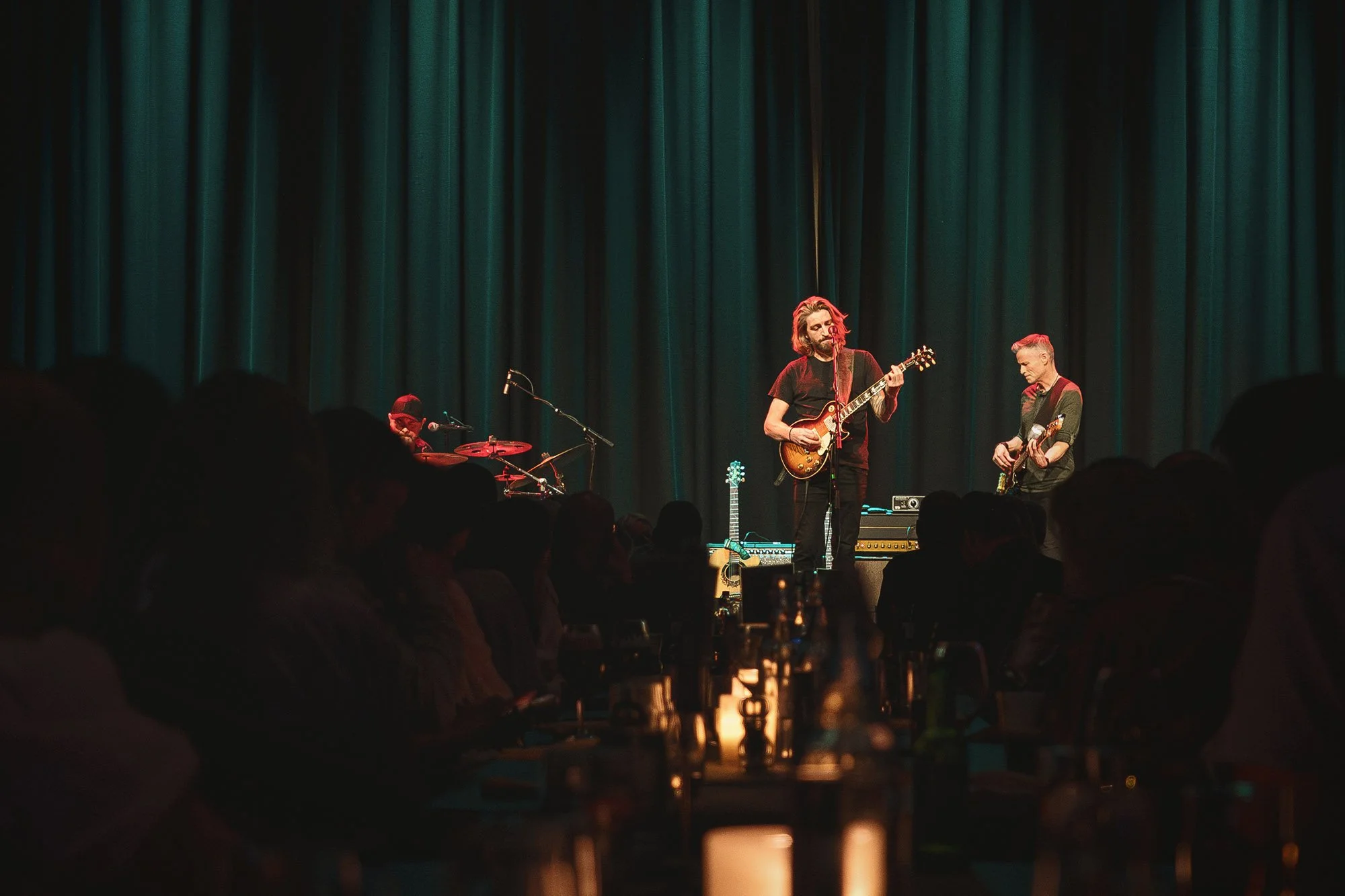 Anders Jektvik står på scenen på Quality Hotel Panorama med gitar i hånden. Publikum koser seg sittende ved bord.