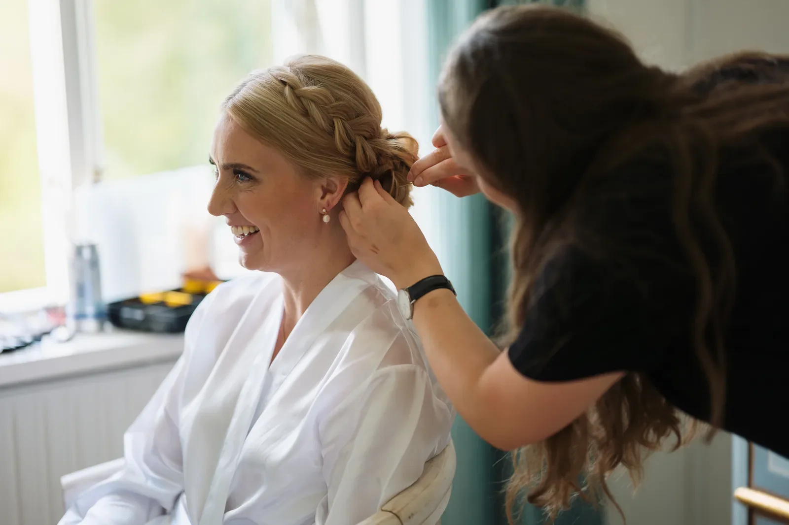 De sidste detaljer på brudens håropsætning med feltning perleøreringe og morgenkåbe