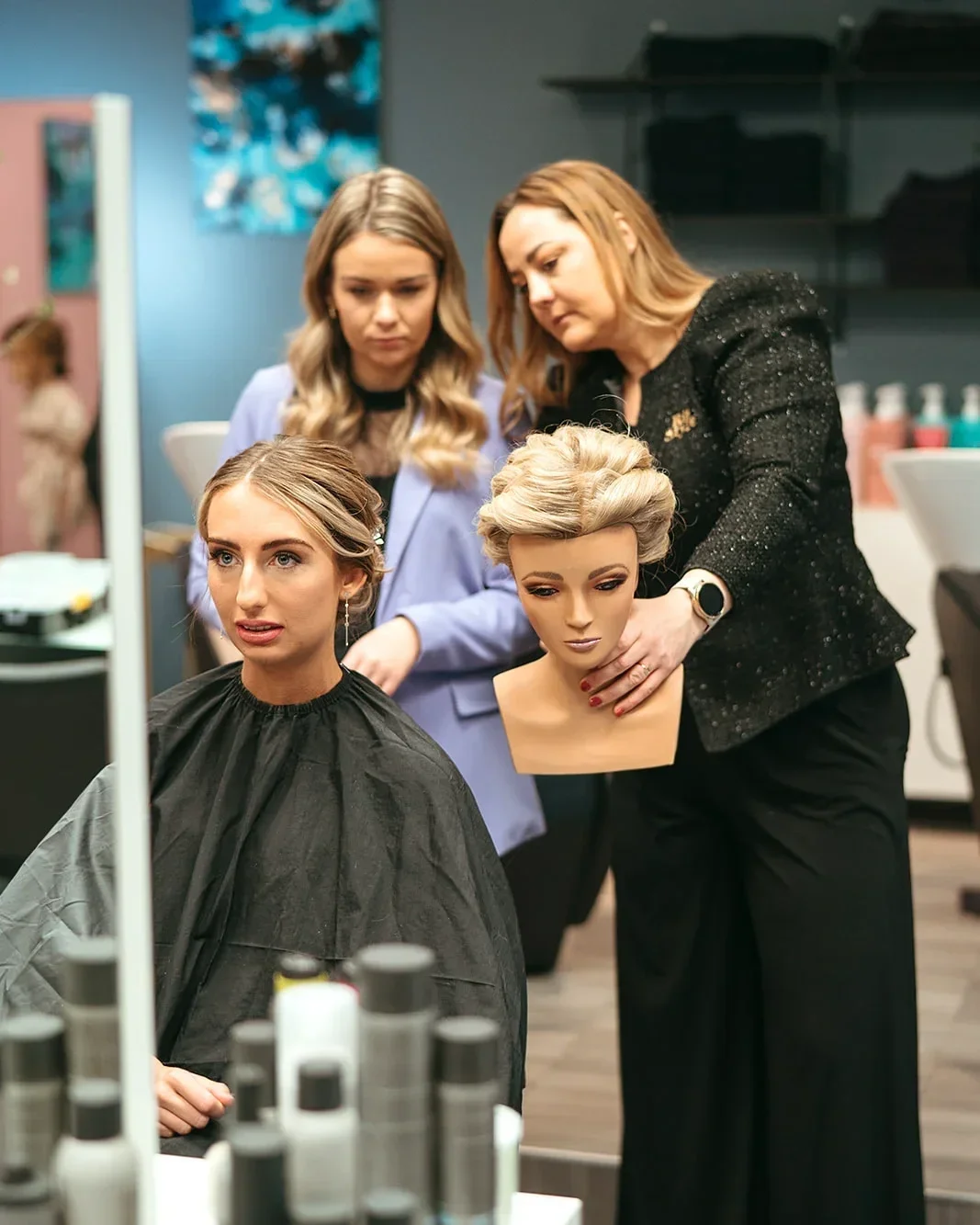 Kvinder sidder ved bord med mad og blomster, en bliver pudset i øjet af en anden, mens en tredje smiler og spiser jordbær.