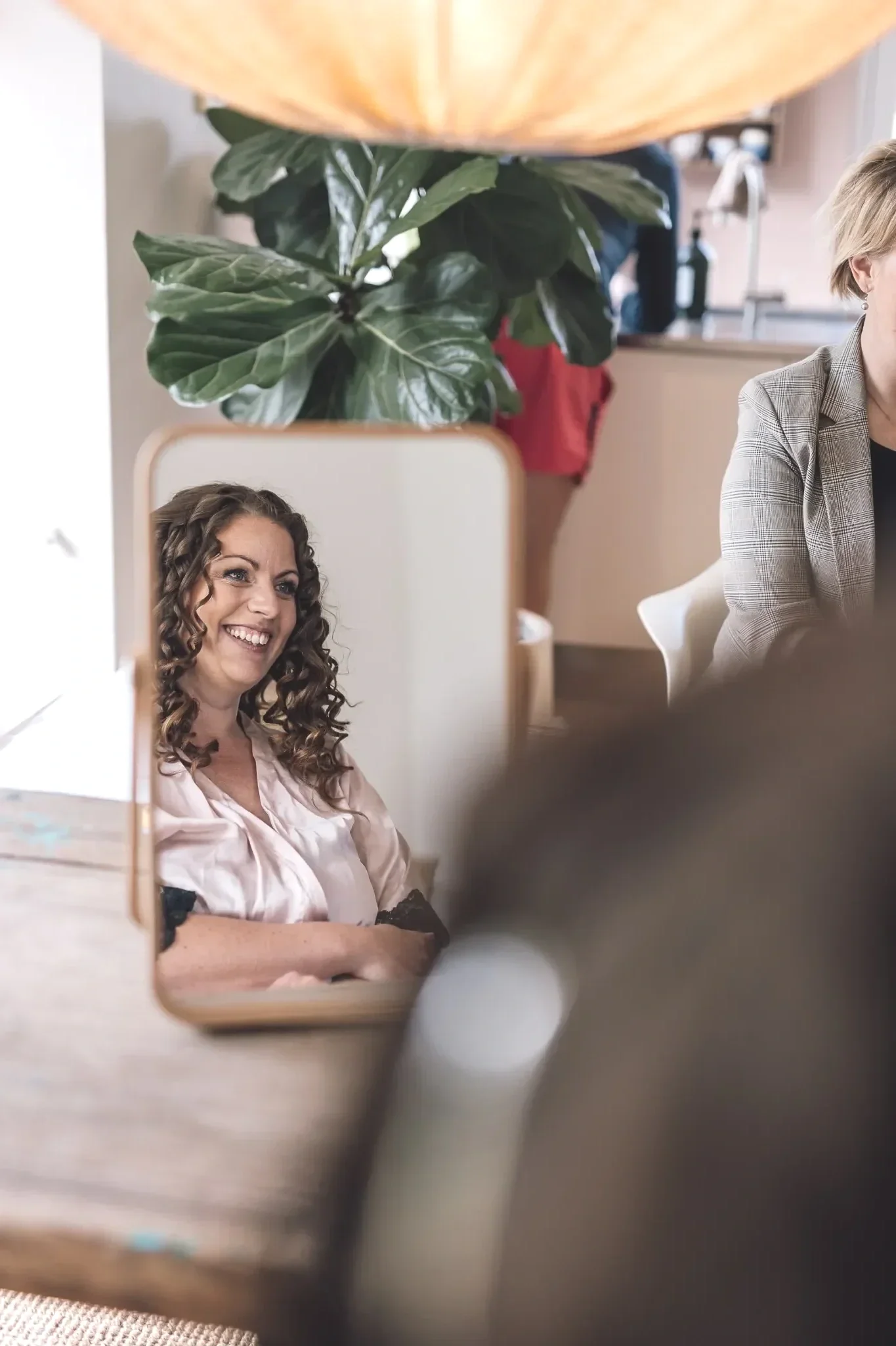 Brud får sat smukt krøllet hår på bryllupsmorgen – afslappet og glad stemning under brudestyling.
